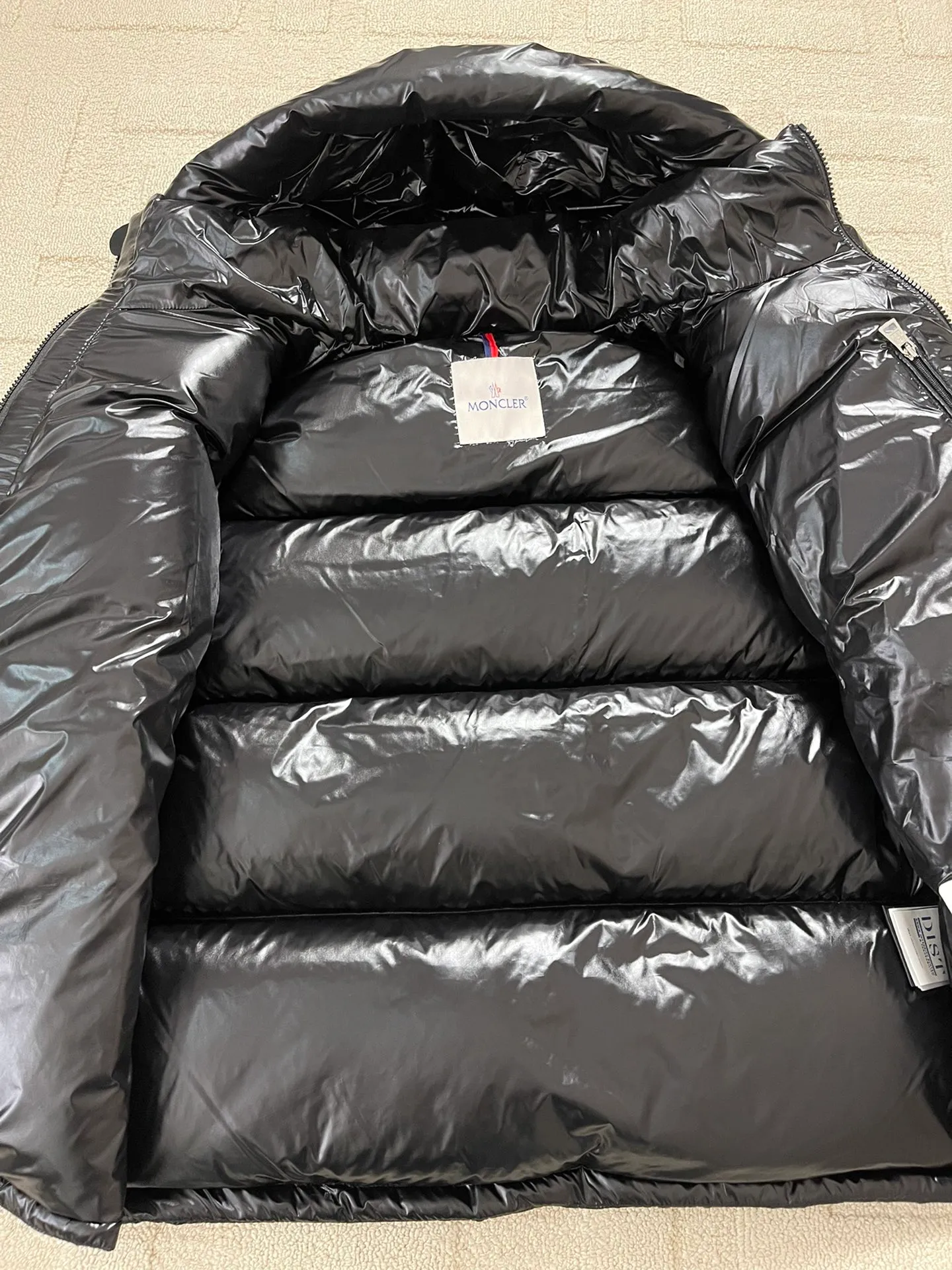 Flat detail P1180 Moncler Montbeliard glossy down jacket The Montbeliard down jacket is made of shiny patented nylon and features highly recognizable rectangular quilting. Featuring a hooded design and signature patch pocket at chest.  Fabric: 100% nylon Filling content: 90% white goose down 250-300g Craftsmanship: Made of nylon laqué fabric Nylon laque lining Filled with down, detachable and adjustable hood with drawstring closure Built-in flap with webbing, black pocket details at the lower end Zipper closure Collar with snap buttons Zipper pockets Patch pockets with snap buttons Adjustable cuffs Adjustable elastic drawstring hem.  Size: 1 2 3 4 5 0548000