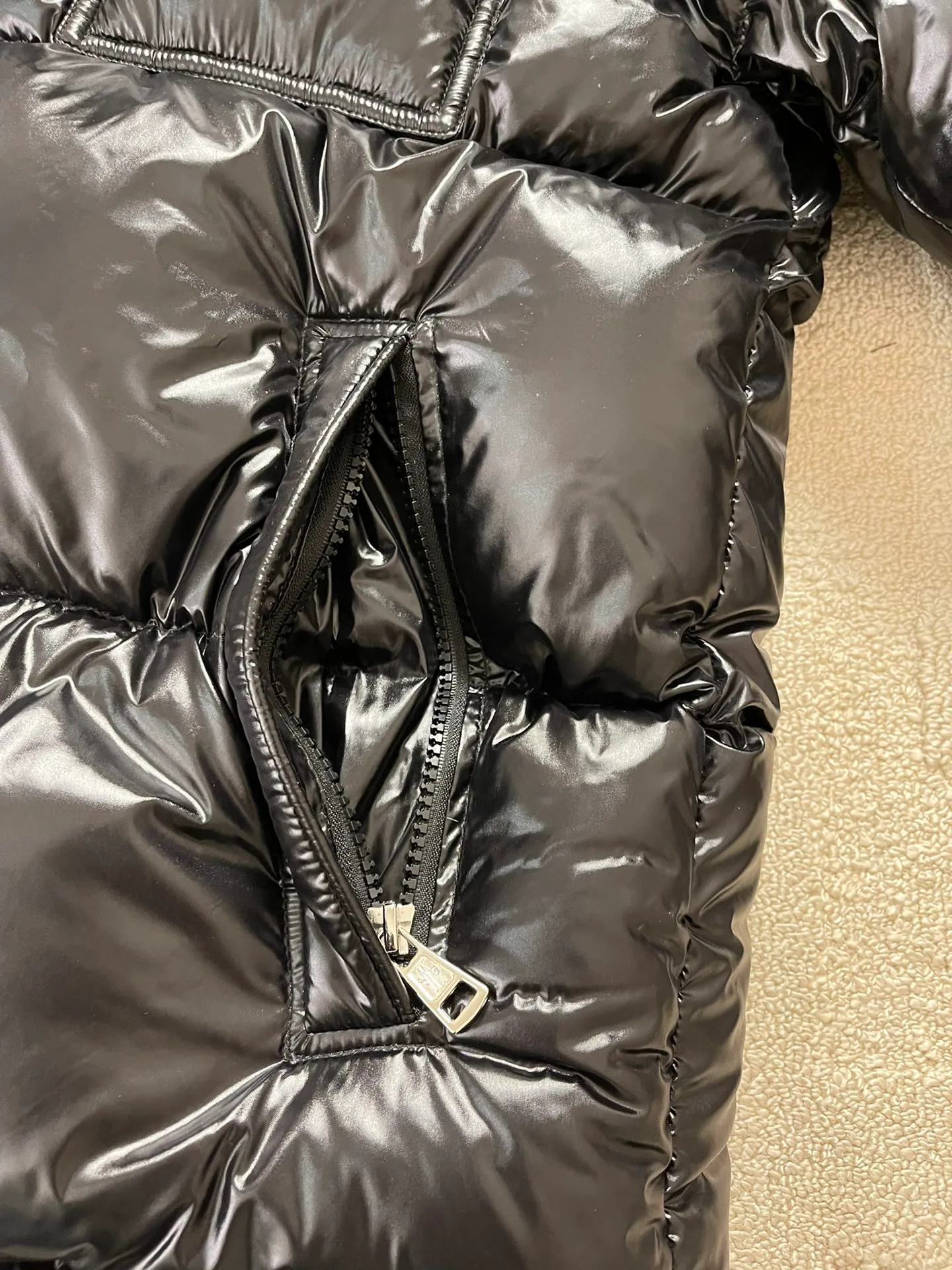 Flat detail P1180 Moncler Montbeliard glossy down jacket The Montbeliard down jacket is made of shiny patented nylon and features highly recognizable rectangular quilting. Featuring a hooded design and signature patch pocket at chest.  Fabric: 100% nylon Filling content: 90% white goose down 250-300g Craftsmanship: Made of nylon laqué fabric Nylon laque lining Filled with down, detachable and adjustable hood with drawstring closure Built-in flap with webbing, black pocket details at the lower end Zipper closure Collar with snap buttons Zipper pockets Patch pockets with snap buttons Adjustable cuffs Adjustable elastic drawstring hem.  Size: 1 2 3 4 5 0548000