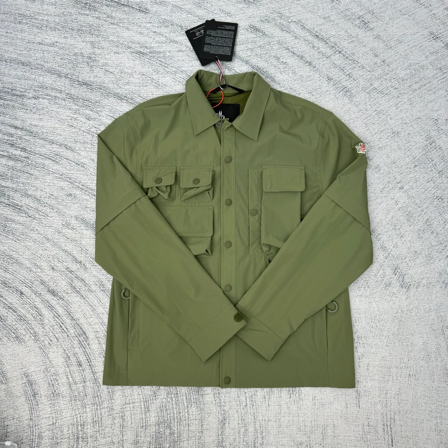 P650 Moncler Grenoble functional outdoor zippered jacket with adjustable sleeves Size: 1/2/3/4 Custom-dyed double stretch mercerized poplin Custom-dyed soft mesh pongee Excellent texture Comfortable and close to the skin Dark green inspired by plant texture The color is taken from sage leaves soaked in morning dew Precision narrative of functional pocket system Balance of function and aesthetics Iconic Moncler logo appears on the sleeves for full recognition The triangular logo of the same color is hidden into the fabric texture like a mark in the undercurrent of the deep sea. It is extremely invisible and visible. The detachable sleeve design allows for diversified outfits.