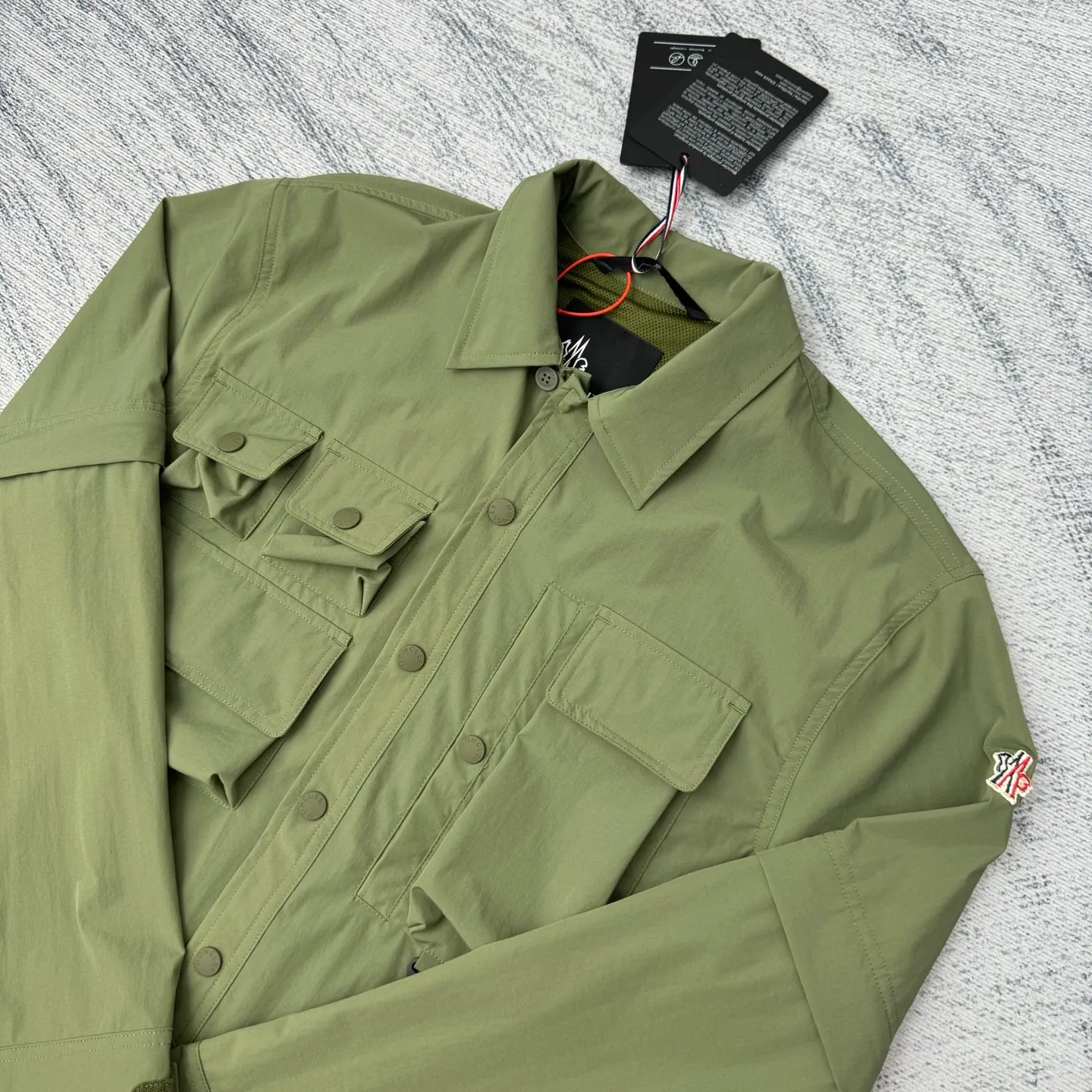 P650 Moncler Grenoble functional outdoor zippered jacket with adjustable sleeves Size: 1/2/3/4 Custom-dyed double stretch mercerized poplin Custom-dyed soft mesh pongee Excellent texture Comfortable and close to the skin Dark green inspired by plant texture The color is taken from sage leaves soaked in morning dew Precision narrative of functional pocket system Balance of function and aesthetics Iconic Moncler logo appears on the sleeves for full recognition The triangular logo of the same color is hidden into the fabric texture like a mark in the undercurrent of the deep sea. It is extremely invisible and visible. The detachable sleeve design allows for diversified outfits.
