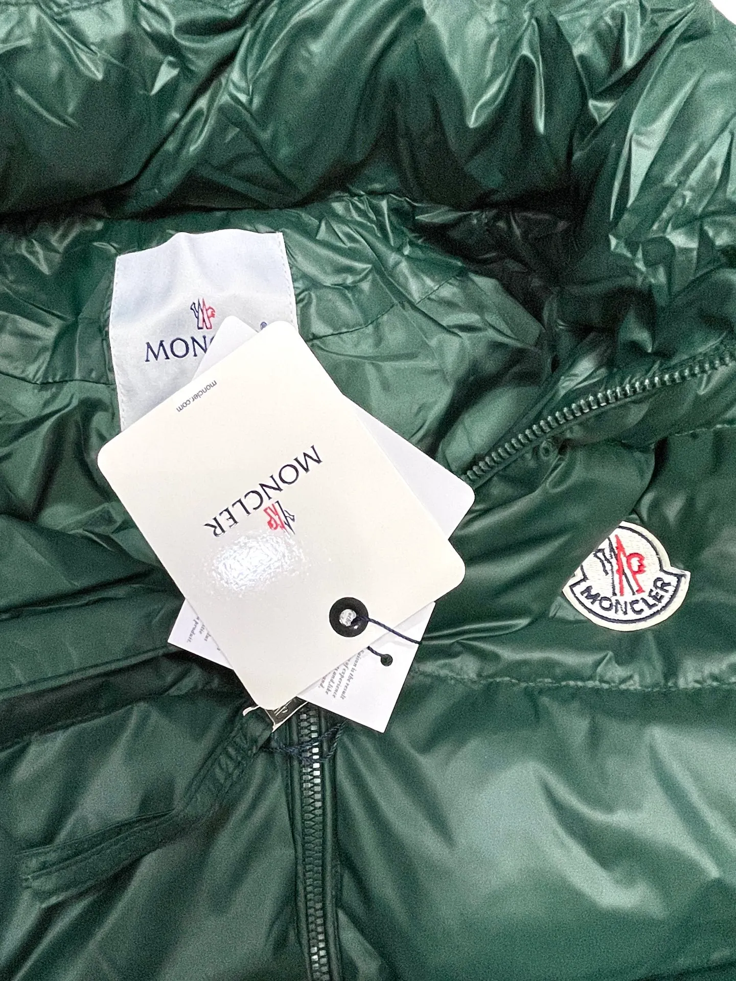 P480 Moncler/Wollaston classic lacquered down jacket. Shows the recognizable Moncler fashion style. Plays with contrasting fabrics. The shiny texture complements the warmth of the down jacket. The hooded style is detachable. It has a modern short design. The Moncler wording on the brim shows the brand charm. Color: black green