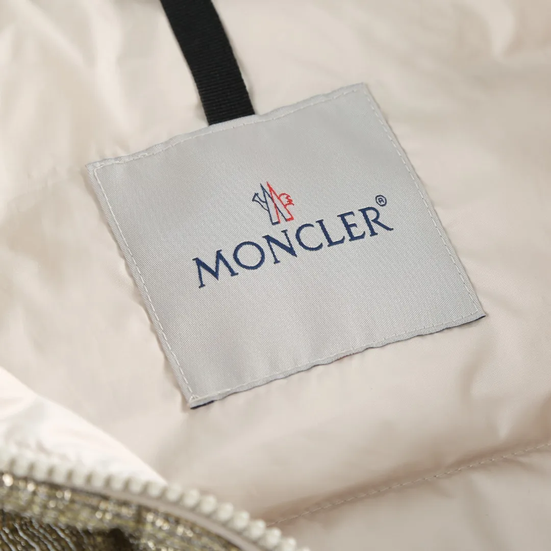 P900 MONCLER gold silk down jacket Fabric selection: Made of 90% 20D ultra-fine nylon and 10% vacuum gold-plated polyester silk. The gold-plated wire is embedded in the nylon base fabric at an oblique angle of 32°. It produces a gradient iridescent effect when illuminated by light, which is comparable to the phantom color gradient of peacock feathers. It forms a visible light spot of 200 meters under the illumination of car lights at night, improving outdoor safety. The high-density woven nylon supports a strong frame with 220 yarns per inch, which effectively locks the down in the physical structure.  Lining selection: High-density lining fabric made of ultra-fine denier, 0.08mm thickness to avoid increasing the overall weight and making it smooth to wear. The high-density woven structure forms a wind resistance layer to protect the thermal efficiency of the thermal layer from loss. It can also withstand the expansion pressure of down and prevent deformation and damage after long-term use.  High-quality filling: 90 white duck down is selected, with a weight of 180g, ensuring excellent thermal insulation performance. After strict screening and processing, the velvet is not easy to get drilled, ensuring durability.  Process: Use anti-velvet silk thread through imported No. 7 needles to reach 13 stitches/inch chain stitch, forming a tight and straight line spacing without skipping stitches. Accessories: One-to-one customized zipper puller, one-to-one customized collar label, one-to-one customized logo SIZE: S M L
