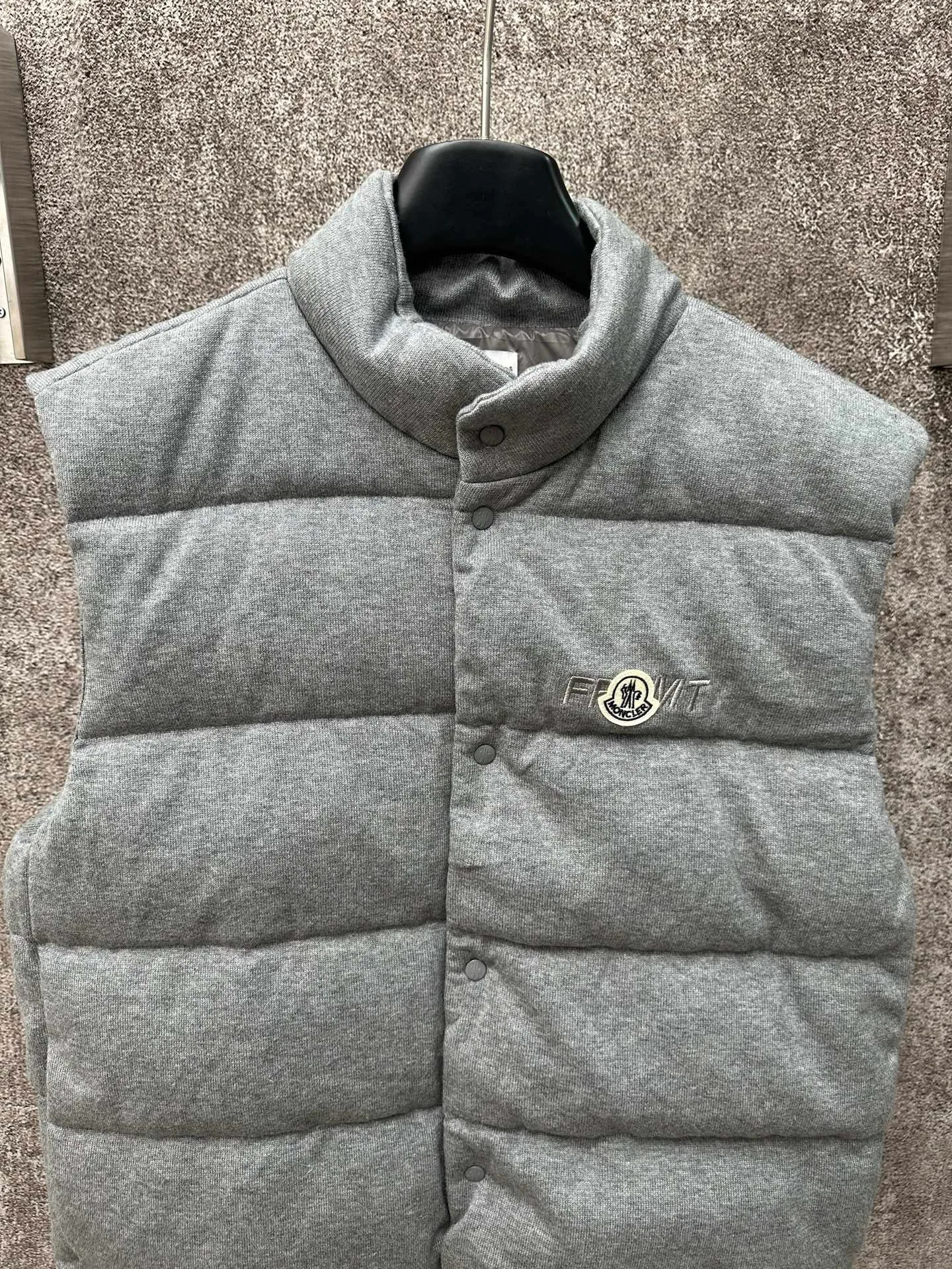 P760 MONCLER cotton embroidered down vest Fabric selection: Lightweight knitted fabric made of 100% cotton fiber. The fiber characteristics are soft to the touch. The knitted structure gives the fabric a certain degree of elasticity in the horizontal and vertical directions. Even though it is a down vest, it can move freely without any sense of restraint. The air circulates freely between the coils and has good breathability. It is not easy to accumulate moisture inside, improving the wearing experience. Lining fabric: The high-density lining is woven with ultra-fine nylon denier, with a thickness of 0.08mm to avoid increasing the overall weight and making it smooth to wear. The high-density woven structure forms a wind resistance layer to protect the thermal efficiency of the thermal layer from loss. It can also withstand the expansion pressure of down and prevent deformation and damage after long-term use.  Process: The high-precision computing system of the computerized embroidery machine controls the coordinated operation of the machine head, needle bar, and bobbin. The fabric frame moves accurately in the horizontal and vertical directions to form a stitch track. The upper and lower thread tensions are adjusted to ensure that the stitches are smooth and free of floating threads. The chest, lower front and lower back panels are decorated with three different letter embroideries. The finished product has clear patterns and no burrs on the edges.  90 national standard high-quality white duck down: Selected high-fill down, with a fill power of 650fp, light and warm, with excellent temperature locking performance and good resilience.  Accessories: One-to-one customized badges, One-to-one customized snaps, One-to-one customized three-label, One-to-one customized zipper pullers SIZE: S M L XL
