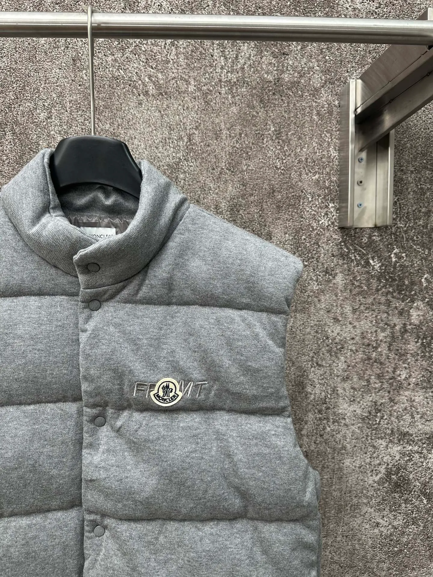 P760 MONCLER cotton embroidered down vest Fabric selection: Lightweight knitted fabric made of 100% cotton fiber. The fiber characteristics are soft to the touch. The knitted structure gives the fabric a certain degree of elasticity in the horizontal and vertical directions. Even though it is a down vest, it can move freely without any sense of restraint. The air circulates freely between the coils and has good breathability. It is not easy to accumulate moisture inside, improving the wearing experience. Lining fabric: The high-density lining is woven with ultra-fine nylon denier, with a thickness of 0.08mm to avoid increasing the overall weight and making it smooth to wear. The high-density woven structure forms a wind resistance layer to protect the thermal efficiency of the thermal layer from loss. It can also withstand the expansion pressure of down and prevent deformation and damage after long-term use.  Process: The high-precision computing system of the computerized embroidery machine controls the coordinated operation of the machine head, needle bar, and bobbin. The fabric frame moves accurately in the horizontal and vertical directions to form a stitch track. The upper and lower thread tensions are adjusted to ensure that the stitches are smooth and free of floating threads. The chest, lower front and lower back panels are decorated with three different letter embroideries. The finished product has clear patterns and no burrs on the edges.  90 national standard high-quality white duck down: Selected high-fill down, with a fill power of 650fp, light and warm, with excellent temperature locking performance and good resilience.  Accessories: One-to-one customized badges, One-to-one customized snaps, One-to-one customized three-label, One-to-one customized zipper pullers SIZE: S M L XL
