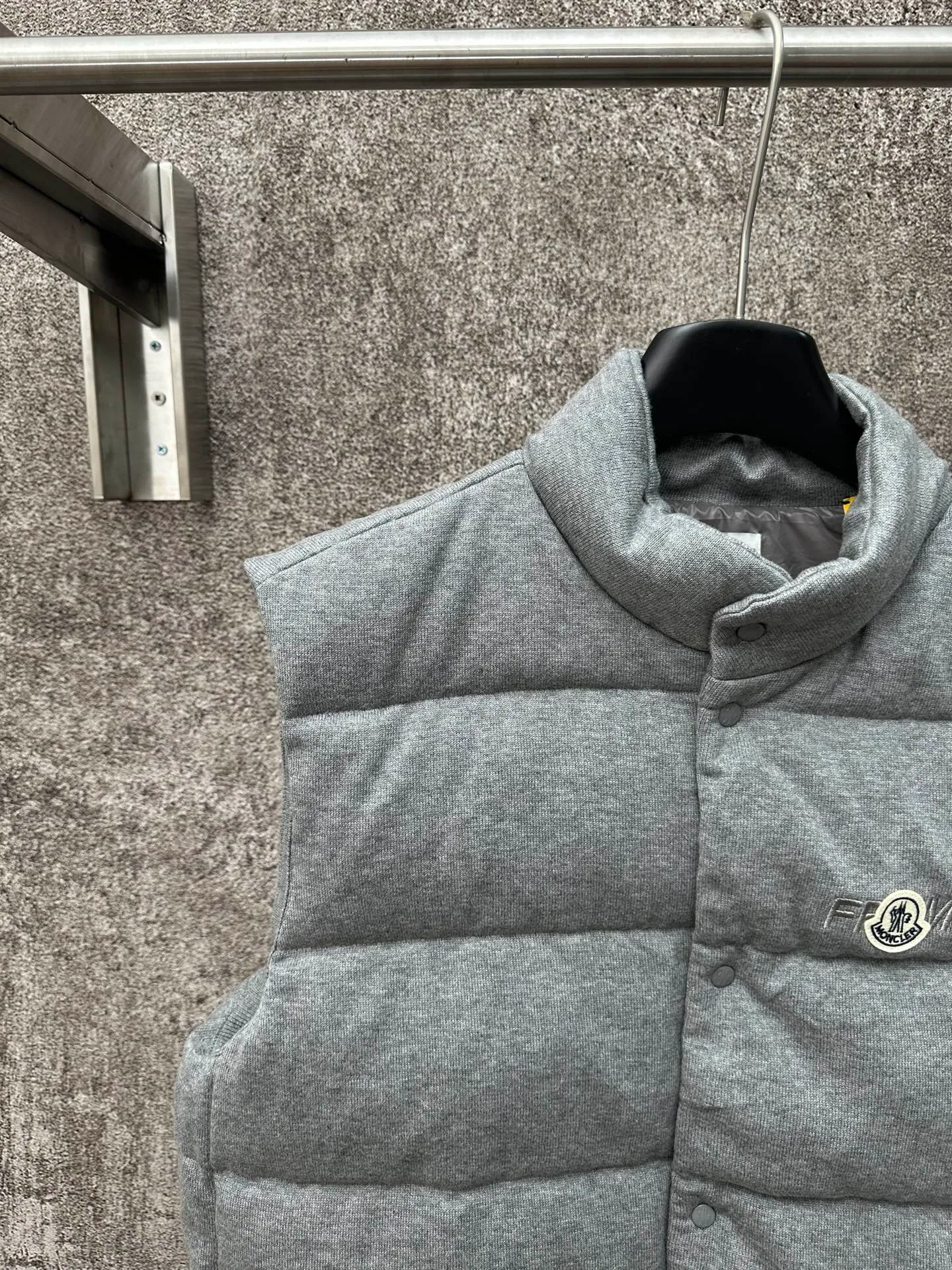 P760 MONCLER cotton embroidered down vest Fabric selection: Lightweight knitted fabric made of 100% cotton fiber. The fiber characteristics are soft to the touch. The knitted structure gives the fabric a certain degree of elasticity in the horizontal and vertical directions. Even though it is a down vest, it can move freely without any sense of restraint. The air circulates freely between the coils and has good breathability. It is not easy to accumulate moisture inside, improving the wearing experience. Lining fabric: The high-density lining is woven with ultra-fine nylon denier, with a thickness of 0.08mm to avoid increasing the overall weight and making it smooth to wear. The high-density woven structure forms a wind resistance layer to protect the thermal efficiency of the thermal layer from loss. It can also withstand the expansion pressure of down and prevent deformation and damage after long-term use.  Process: The high-precision computing system of the computerized embroidery machine controls the coordinated operation of the machine head, needle bar, and bobbin. The fabric frame moves accurately in the horizontal and vertical directions to form a stitch track. The upper and lower thread tensions are adjusted to ensure that the stitches are smooth and free of floating threads. The chest, lower front and lower back panels are decorated with three different letter embroideries. The finished product has clear patterns and no burrs on the edges.  90 national standard high-quality white duck down: Selected high-fill down, with a fill power of 650fp, light and warm, with excellent temperature locking performance and good resilience.  Accessories: One-to-one customized badges, One-to-one customized snaps, One-to-one customized three-label, One-to-one customized zipper pullers SIZE: S M L XL