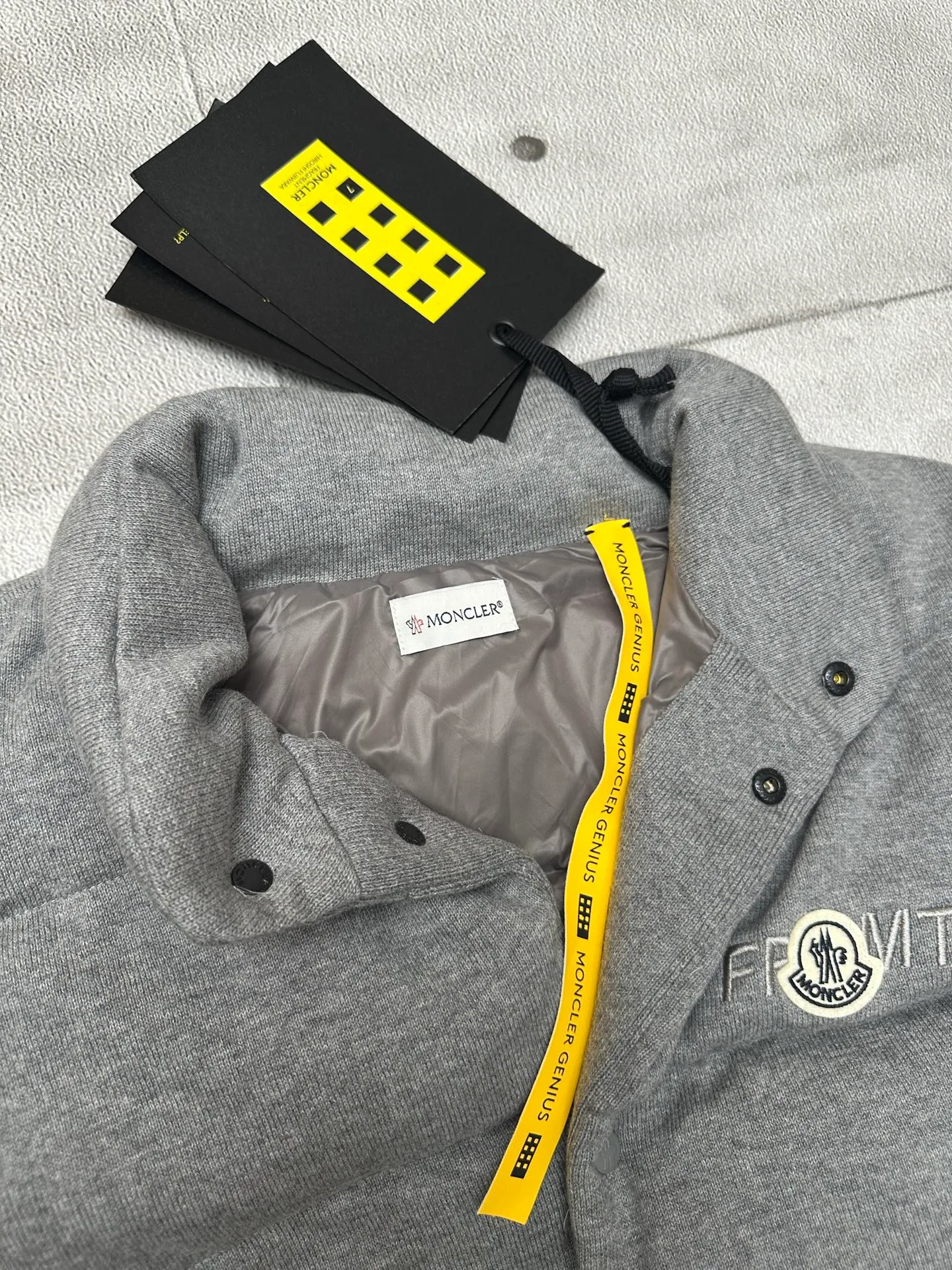P760 MONCLER cotton embroidered down vest Fabric selection: Lightweight knitted fabric made of 100% cotton fiber. The fiber characteristics are soft to the touch. The knitted structure gives the fabric a certain degree of elasticity in the horizontal and vertical directions. Even though it is a down vest, it can move freely without any sense of restraint. The air circulates freely between the coils and has good breathability. It is not easy to accumulate moisture inside, improving the wearing experience. Lining fabric: The high-density lining is woven with ultra-fine nylon denier, with a thickness of 0.08mm to avoid increasing the overall weight and making it smooth to wear. The high-density woven structure forms a wind resistance layer to protect the thermal efficiency of the thermal layer from loss. It can also withstand the expansion pressure of down and prevent deformation and damage after long-term use.  Process: The high-precision computing system of the computerized embroidery machine controls the coordinated operation of the machine head, needle bar, and bobbin. The fabric frame moves accurately in the horizontal and vertical directions to form a stitch track. The upper and lower thread tensions are adjusted to ensure that the stitches are smooth and free of floating threads. The chest, lower front and lower back panels are decorated with three different letter embroideries. The finished product has clear patterns and no burrs on the edges.  90 national standard high-quality white duck down: Selected high-fill down, with a fill power of 650fp, light and warm, with excellent temperature locking performance and good resilience.  Accessories: One-to-one customized badges, One-to-one customized snaps, One-to-one customized three-label, One-to-one customized zipper pullers SIZE: S M L XL