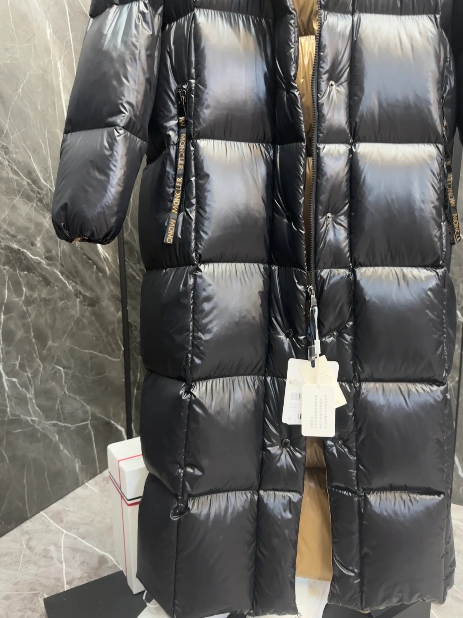 Premium down  Parnaiba's long down jacket features graphic details and bold color blocking in signature patented nylon. The eye-catching design features large grille quilting and contrasting lining. The removable hood and adjustable hem make it easy to personalize the style, and the color-blocked pattern highlights the highly recognizable Moncler vibe. Details •Made from nylon laqué fabric •Contrast nylon laqué lining •Detachable hood with zipper and drawstring •Zip closure with black patented snap fastener •Zip pocket Size: 0-4. Original runs large. D98108078950