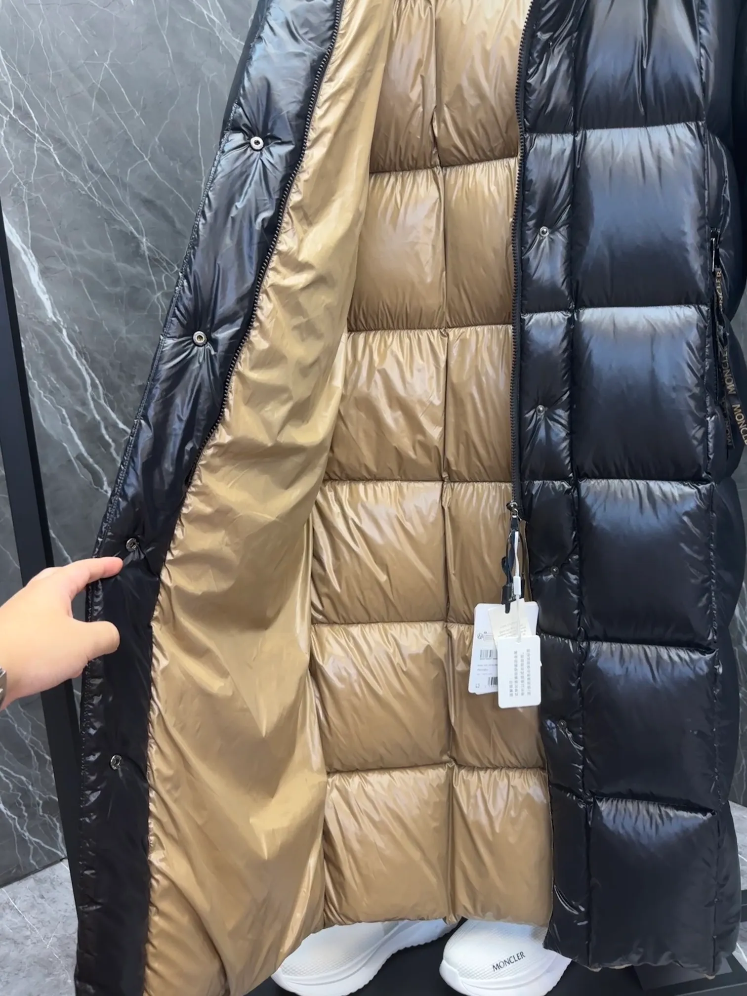 Premium down  Parnaiba's long down jacket features graphic details and bold color blocking in signature patented nylon. The eye-catching design features large grille quilting and contrasting lining. The removable hood and adjustable hem make it easy to personalize the style, and the color-blocked pattern highlights the highly recognizable Moncler vibe. Details •Made from nylon laqué fabric •Contrast nylon laqué lining •Detachable hood with zipper and drawstring •Zip closure with black patented snap fastener •Zip pocket Size: 0-4. Original runs large. D98108078950