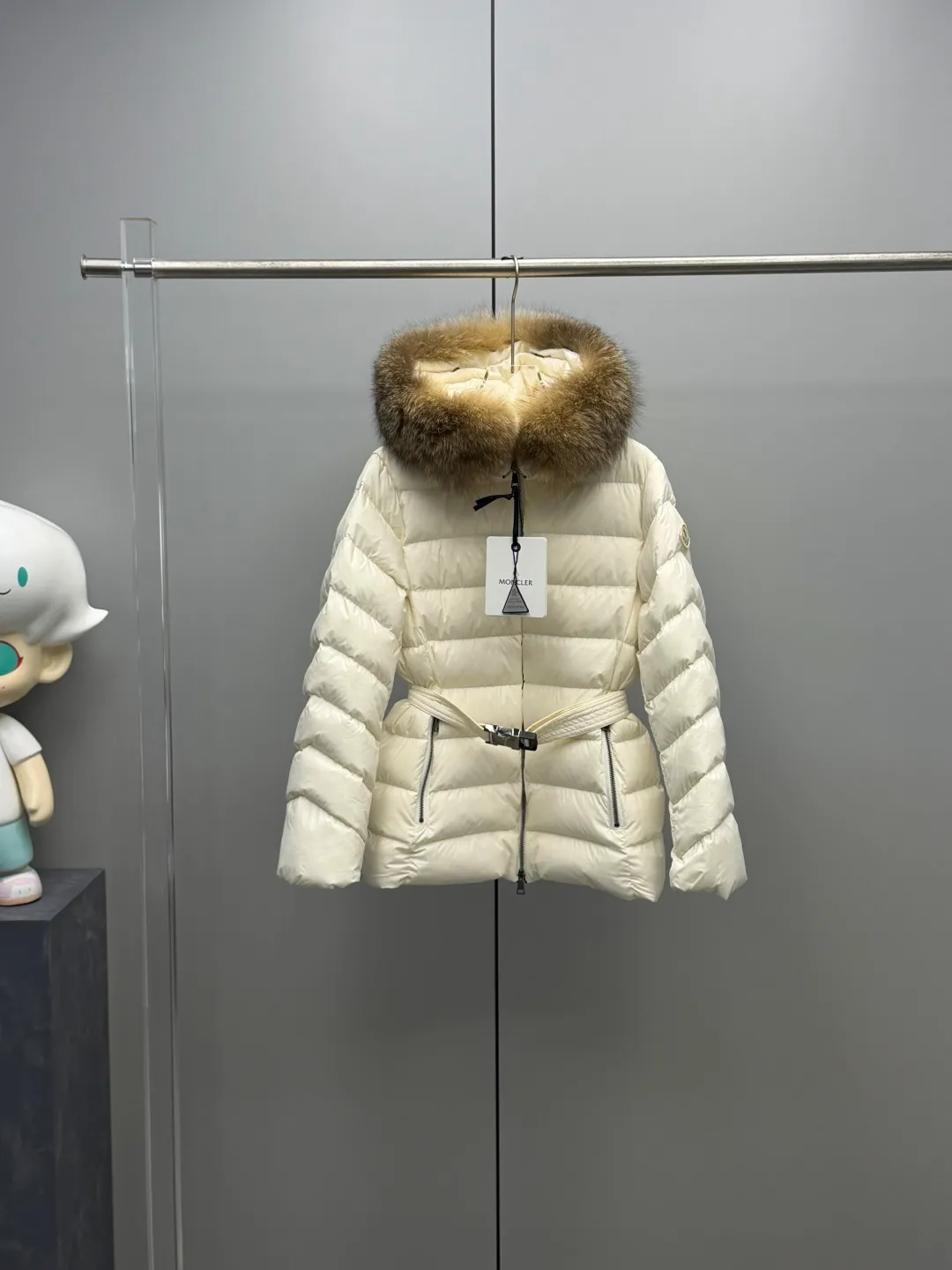 P1180 MONCLER 2025FW Women's Cupidone Large Fur Collar Small Waist Slim Belt Hooded Down Jacket Three-dimensional girdle design: innovatively uses an adjustable belt to accurately outline women's waist curves, effectively enhance the waistline, reshape the golden body proportions, and completely bid farewell to the bloated feeling of traditional down jackets. A-line micro silhouette: tall and straight upper body, slightly flared hem, elegance and agility coexist. Symbol of luxury | Oversized fur collar, choose a large fur collar: The brim of the hat is decorated with a luxurious and fluffy large fur collar, which not only provides the ultimate in warmth and care, but also demonstrates extraordinary taste and strong aura. High-quality fleece core: uniform fleece filling and temperature locking technology to ensure that it remains warm as spring in extremely cold environments. Whether paired with skinny jeans to create a casual fashion, or worn under a dress to show elegance. Color: Milky white, brown, black Size: 1-2-3-4