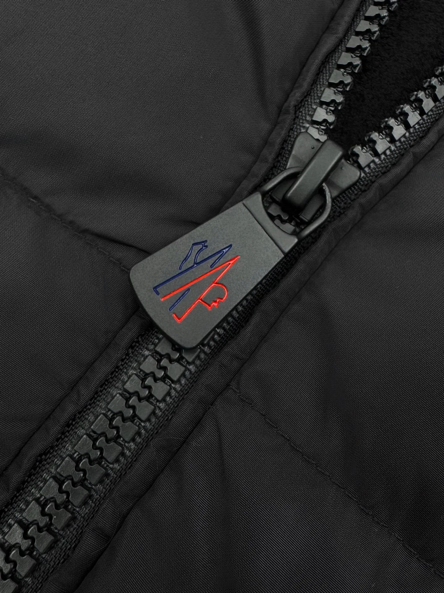 P780 Moncler logo woven splicing down jacket, custom matte lattice air shield down and 300D high-density calendered coating, using the new national standard 90 white duck down (welcome to test), full of down, full of warmth, light and fluffy, with a pure and extreme black tone, exuding an irresistible charm. The Monlcer triangle logo is embellished on the chest. The power aesthetics of the minimalist logo. The concentrated down filling in the front area creates dynamic insulation for the core heat dissipation zone of the human body. The hooded down is a moving warm flow barrier for the head and neck. It forms a thermal energy circulation system with the front panel. The elastic woven sleeves provide freedom of movement with a sense of compression, forming a relaxed and warm philosophy. The real high-end is to let function become the footnote of style. Process 1: Computer mechanical down filling. First, make the liner pattern to determine the filling area and determine the gram weight of down per square meter according to the original three-dimensional effect to calculate the amount of down filling for each piece. The computer down filling machine uses a digital weighing unit. Achieve stable measurement Process 2: 3D three-dimensional quilting technology. With the help of the programming system of the CNC quilting machine, the down in different areas is accurately separated to ensure that the filling is evenly fixed after sewing to avoid agglomeration or shifting. Process 3: Computer template machine line running process. The computer template machine line running process shows extremely high neatness and smoothness. The craftsman accurately controls the size during the operation to ensure that each row line meets the design requirements. The lines of the entire template are smooth and unified, clean and beautiful. Process 4: Triple locking and five-thread dense stitching process. Main seam locking + diagonal reinforcement + raw edge wrapping. Triple structure to form a three-dimensional protective net at the edge of the fabric to avoid stitch breakage. Paving materials: Customized 1:1 Moncler zipper. Customized 1:1 Moncler rope loop. Customized 1:1 Moncler logo. Customized 1:1 Moncler eyelet. Customized 1:1 Moncler trademark. Size: S M L XL Style number: 25378
