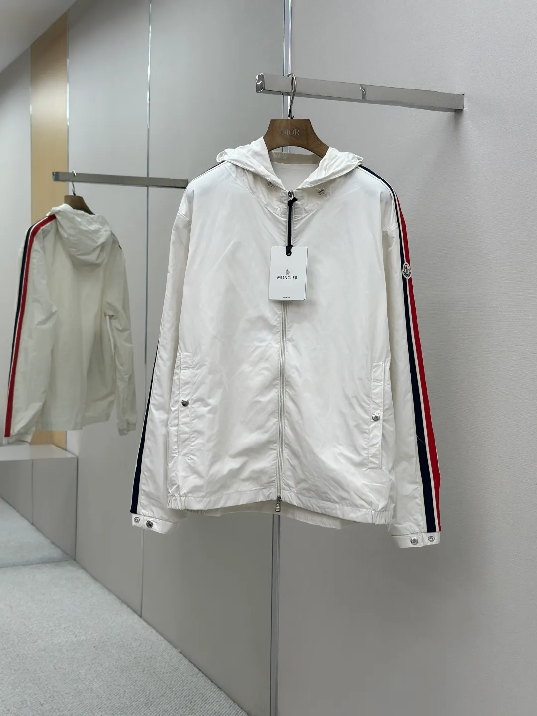 P560 MONCLER web-trimmed lightweight jacket Fabric selection: 100% polyester fiber is used to create a tough protective outer layer. It is known for its excellent tear resistance and wear resistance. It can quickly return to flatness during wearing and maintain the crisp and stylish appearance of the clothing for a long time. At the same time, it is not easy to deform after being washed for a long time.   Features: Two different colored decorative strips added to the center part of the sleeves. This design element can not only add visual highlights to clothing, making it more fashionable and unique. Craftsmanship: The webbing is precisely positioned along the cuffs to the seam of the collar and hat to ensure symmetry and overall smoothness. Before actual sewing, use very fine basting stitches for pre-fixing. This step is crucial to prevent the webbing from slipping, twisting, or wrinkling during sewing and ensuring that the final stitch is straight and perfect.  Accessories: Custom zipper puller, custom buttons with logo, custom hood drawstring elastic buckle SIZE: 1 2 3 4