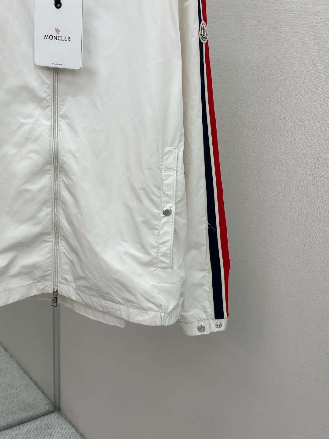 P560 MONCLER web-trimmed lightweight jacket Fabric selection: 100% polyester fiber is used to create a tough protective outer layer. It is known for its excellent tear resistance and wear resistance. It can quickly return to flatness during wearing and maintain the crisp and stylish appearance of the clothing for a long time. At the same time, it is not easy to deform after being washed for a long time.   Features: Two different colored decorative strips added to the center part of the sleeves. This design element can not only add visual highlights to clothing, making it more fashionable and unique. Craftsmanship: The webbing is precisely positioned along the cuffs to the seam of the collar and hat to ensure symmetry and overall smoothness. Before actual sewing, use very fine basting stitches for pre-fixing. This step is crucial to prevent the webbing from slipping, twisting, or wrinkling during sewing and ensuring that the final stitch is straight and perfect.  Accessories: Custom zipper puller, custom buttons with logo, custom hood drawstring elastic buckle SIZE: 1 2 3 4