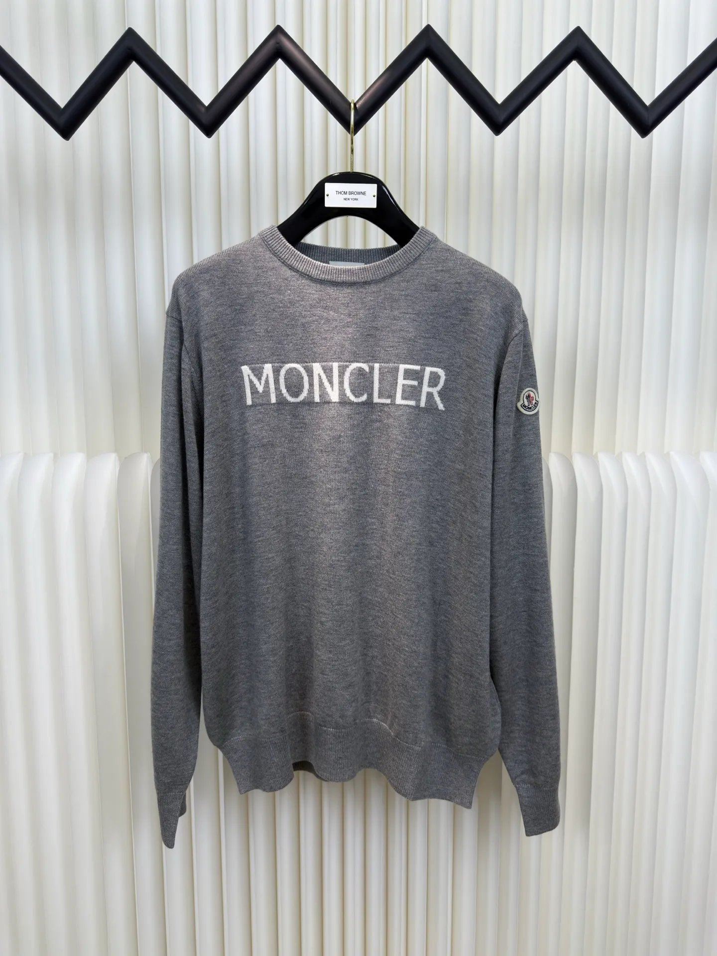 P440 MONCLER jacquard crew neck sweater is made of wool blended fabric, mainly 95% wool, combined with 4% nylon and 1% spandex. The main body of wool ensures the warmth and comfort of the clothing. The addition of a small amount of nylon and spandex significantly improves the elasticity and wear resistance. The ribbed decorative parts are made of 100% wool, which further enhances the overall texture.  Through the high needle count and fine gauge loom, combined with the orderly direction of the internal yarn, the floating threads are cleverly woven and stored, with almost no unnecessary thread mess. The color switching of each group of letters is synchronized with the knitting needles in milliseconds, forming a delicate letter LOGO jacquard decoration on the chest. Size S M L XL