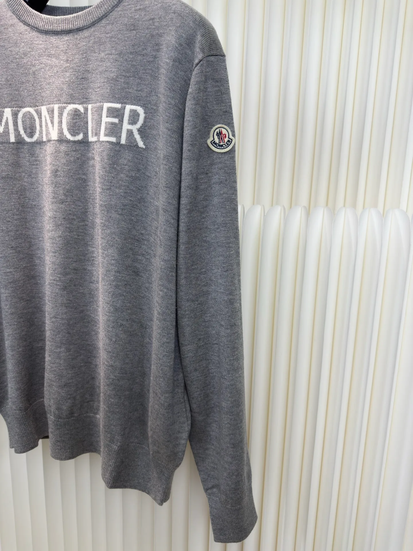 P440 MONCLER jacquard crew neck sweater is made of wool blended fabric, mainly 95% wool, combined with 4% nylon and 1% spandex. The main body of wool ensures the warmth and comfort of the clothing. The addition of a small amount of nylon and spandex significantly improves the elasticity and wear resistance. The ribbed decorative parts are made of 100% wool, which further enhances the overall texture.  Through the high needle count and fine gauge loom, combined with the orderly direction of the internal yarn, the floating threads are cleverly woven and stored, with almost no unnecessary thread mess. The color switching of each group of letters is synchronized with the knitting needles in milliseconds, forming a delicate letter LOGO jacquard decoration on the chest. Size S M L XL