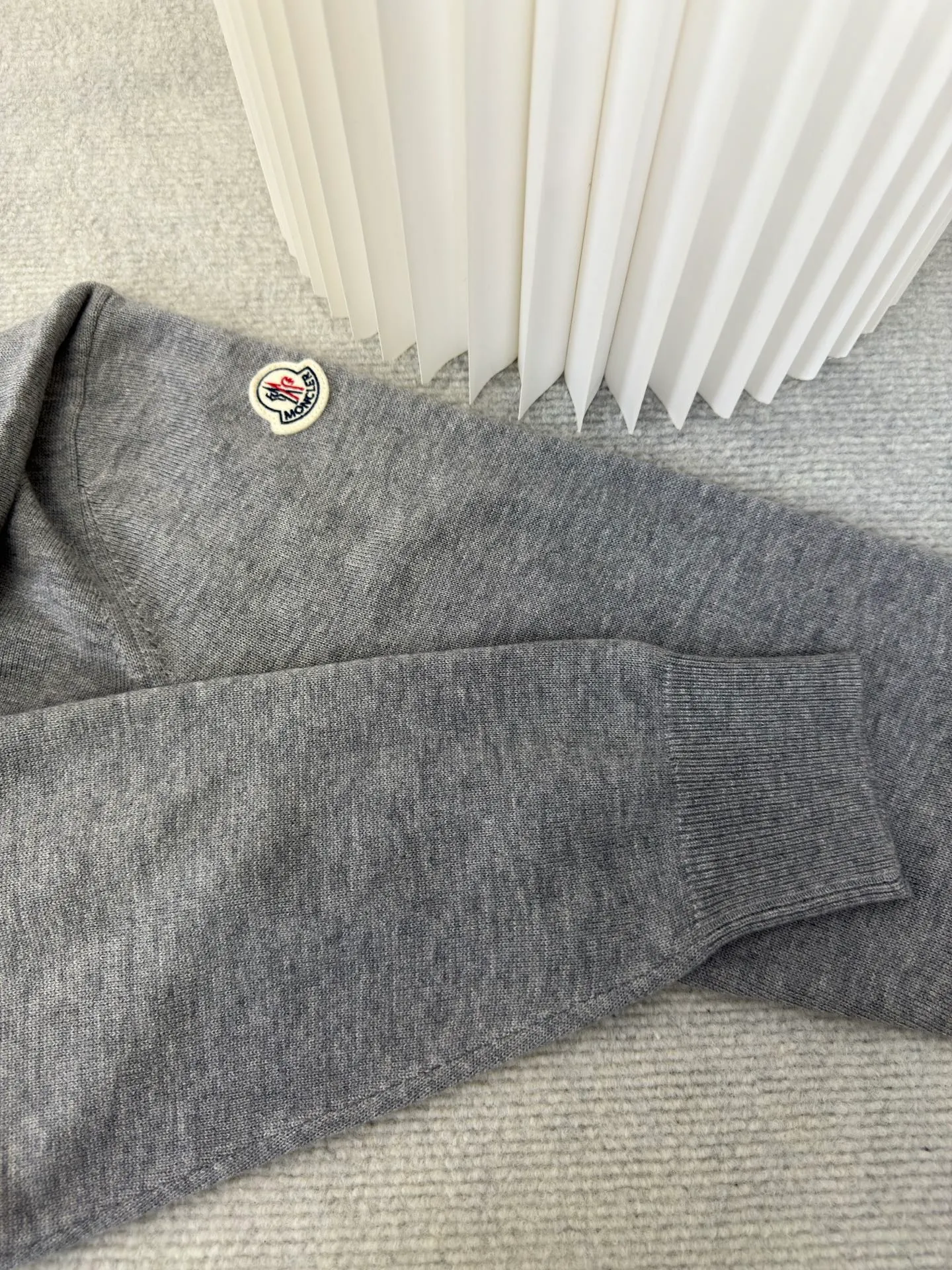 P440 MONCLER jacquard crew neck sweater is made of wool blended fabric, mainly 95% wool, combined with 4% nylon and 1% spandex. The main body of wool ensures the warmth and comfort of the clothing. The addition of a small amount of nylon and spandex significantly improves the elasticity and wear resistance. The ribbed decorative parts are made of 100% wool, which further enhances the overall texture.  Through the high needle count and fine gauge loom, combined with the orderly direction of the internal yarn, the floating threads are cleverly woven and stored, with almost no unnecessary thread mess. The color switching of each group of letters is synchronized with the knitting needles in milliseconds, forming a delicate letter LOGO jacquard decoration on the chest. Size S M L XL