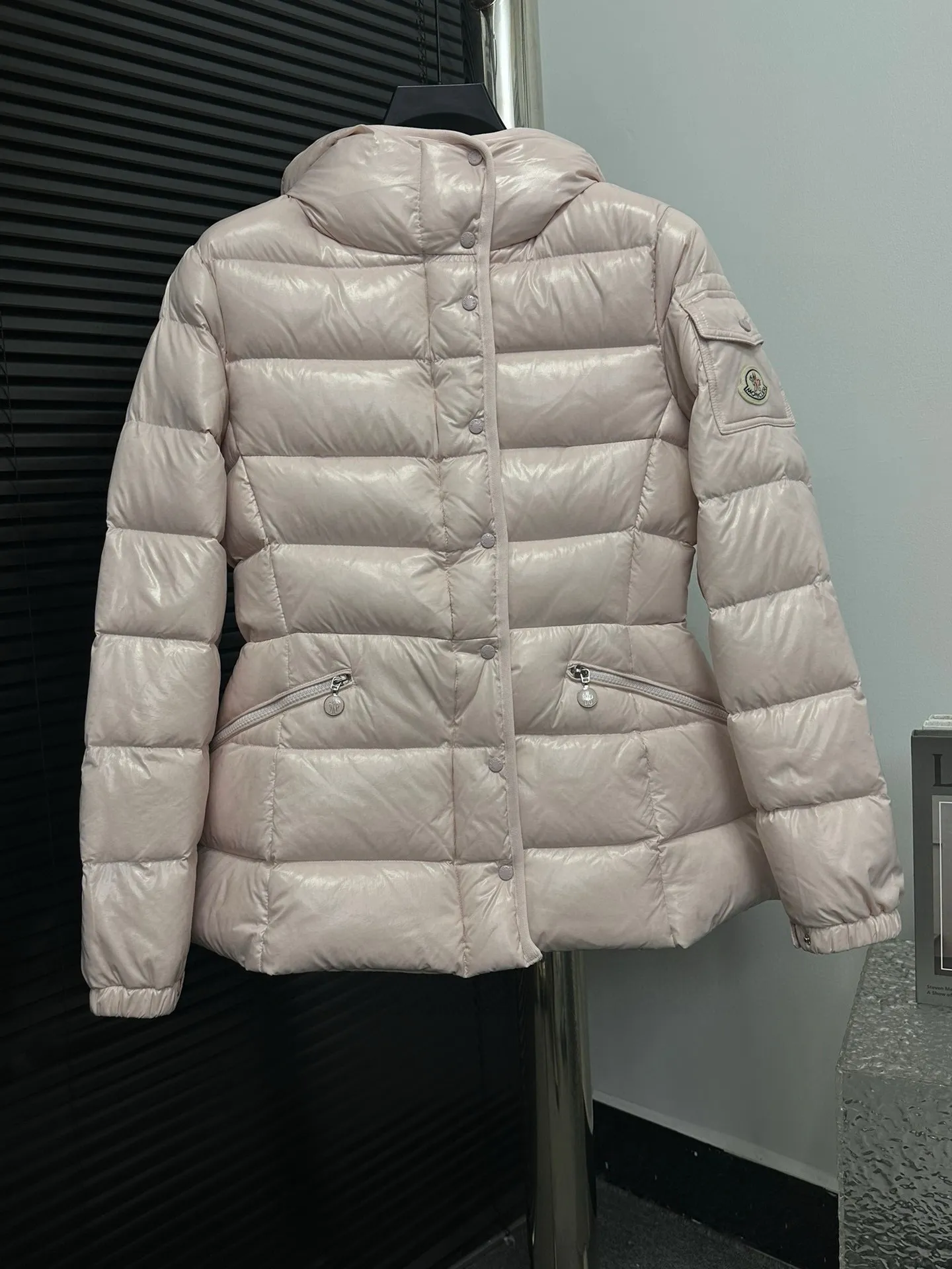 P860 [Moncler] Hooded, waisted women's short down jacket. The barante down jacket is made of glossy nylon fabric and is inspired by the 1970s. It adopts a waist design and presents an A-line silhouette, highlighting a feminine style. An adjustable hood and signature logo patch add finishing touches. Details · Made of lon laqué fabric · lon laqué lining · Filled with down · Adjustable hood · Zipper and snap closure · Suit pocket · Adjustable cuffs Size: 0/1/2/3