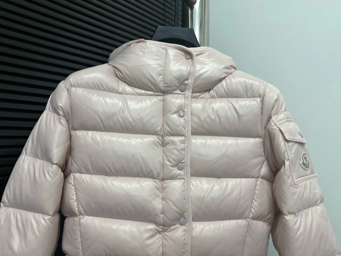 P860 [Moncler] Hooded, waisted women's short down jacket. The barante down jacket is made of glossy nylon fabric and is inspired by the 1970s. It adopts a waist design and presents an A-line silhouette, highlighting a feminine style. An adjustable hood and signature logo patch add finishing touches. Details · Made of lon laqué fabric · lon laqué lining · Filled with down · Adjustable hood · Zipper and snap closure · Suit pocket · Adjustable cuffs Size: 0/1/2/3