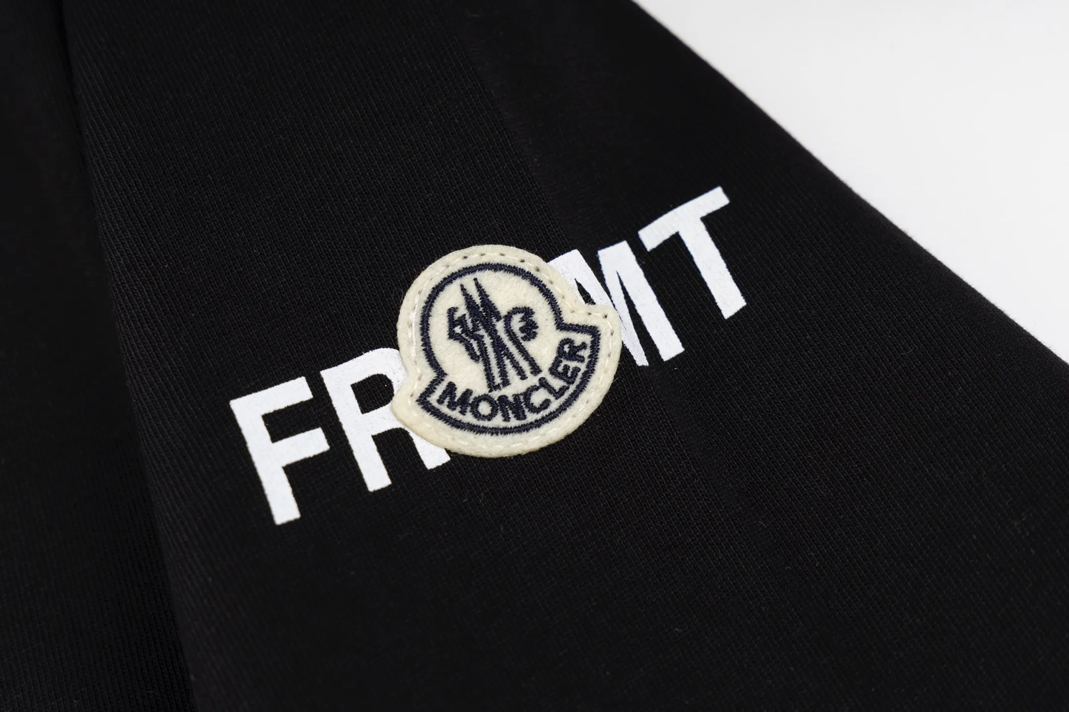 P230 exclusive supply] Moncler Hiroshi Fujiwara co-branded short-sleeve (black) is made of double-ply cotton plain fabric. The warp and weft yarns are interwoven one up and down to form a uniform grid-like texture, with a tight but light structure. Cotton fiber has natural breathability and skin-friendly properties. Combined with the pore structure of plain weave, it is suitable for daily perspiration needs and has good wearing comfort. The yarn has many intertwining points, which strengthens the tear resistance and can maintain its shape after multiple washings. Four high-saturation patterns are presented on the fabric through glue printing. The scraper pressure is even and the scraping is performed in three steps to ensure that the glue is fully penetrated and covered. After curing at high temperature, the pigment is firmly bonded to the cotton fiber. The ink-absorbing and penetrating properties of the cotton fiber make the pattern less likely to fall off due to friction. By actively interfering with the shrinkage potential of cotton fibers, the fabric is able to transition from changeable to stable, improving dimensional stability while being less prone to deformation and wrinkles. Size:S-M-L-XL