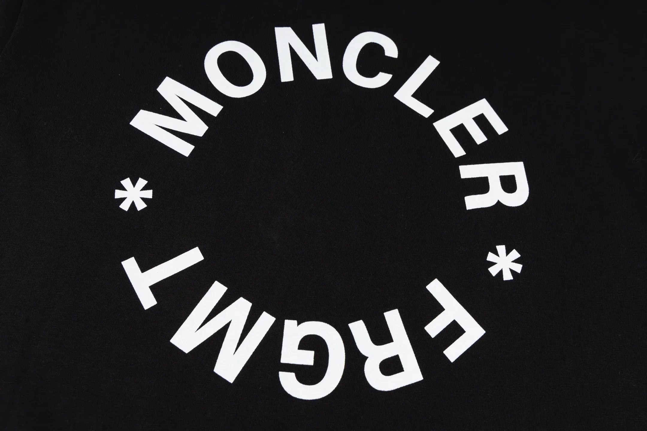 P230 exclusive supply] Moncler Hiroshi Fujiwara co-branded short-sleeve (black) is made of double-ply cotton plain fabric. The warp and weft yarns are interwoven one up and down to form a uniform grid-like texture, with a tight but light structure. Cotton fiber has natural breathability and skin-friendly properties. Combined with the pore structure of plain weave, it is suitable for daily perspiration needs and has good wearing comfort. The yarn has many intertwining points, which strengthens the tear resistance and can maintain its shape after multiple washings. Four high-saturation patterns are presented on the fabric through glue printing. The scraper pressure is even and the scraping is performed in three steps to ensure that the glue is fully penetrated and covered. After curing at high temperature, the pigment is firmly bonded to the cotton fiber. The ink-absorbing and penetrating properties of the cotton fiber make the pattern less likely to fall off due to friction. By actively interfering with the shrinkage potential of cotton fibers, the fabric is able to transition from changeable to stable, improving dimensional stability while being less prone to deformation and wrinkles. Size:S-M-L-XL