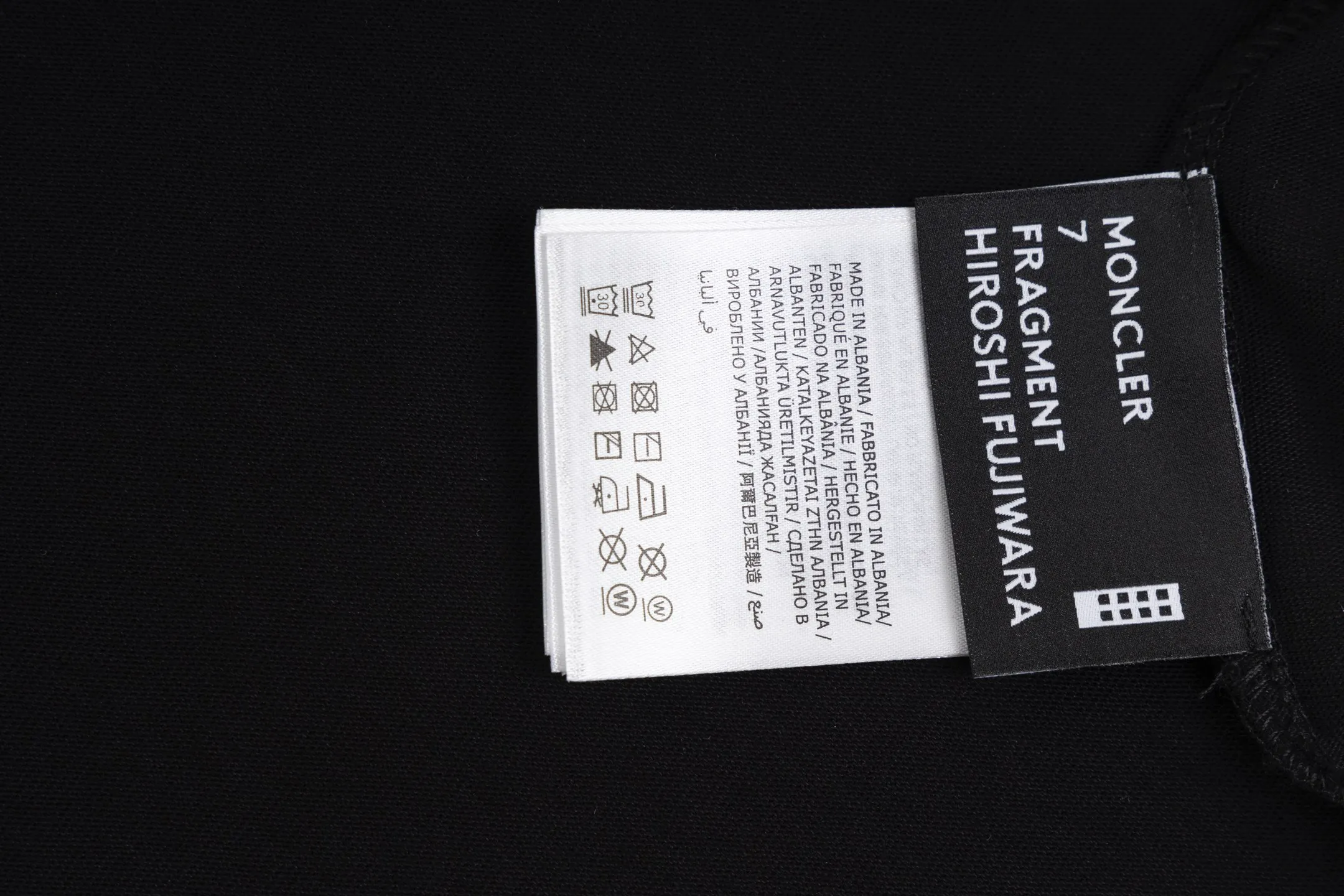 P230 exclusive supply] Moncler Hiroshi Fujiwara co-branded short-sleeve (black) is made of double-ply cotton plain fabric. The warp and weft yarns are interwoven one up and down to form a uniform grid-like texture, with a tight but light structure. Cotton fiber has natural breathability and skin-friendly properties. Combined with the pore structure of plain weave, it is suitable for daily perspiration needs and has good wearing comfort. The yarn has many intertwining points, which strengthens the tear resistance and can maintain its shape after multiple washings. Four high-saturation patterns are presented on the fabric through glue printing. The scraper pressure is even and the scraping is performed in three steps to ensure that the glue is fully penetrated and covered. After curing at high temperature, the pigment is firmly bonded to the cotton fiber. The ink-absorbing and penetrating properties of the cotton fiber make the pattern less likely to fall off due to friction. By actively interfering with the shrinkage potential of cotton fibers, the fabric is able to transition from changeable to stable, improving dimensional stability while being less prone to deformation and wrinkles. Size:S-M-L-XL