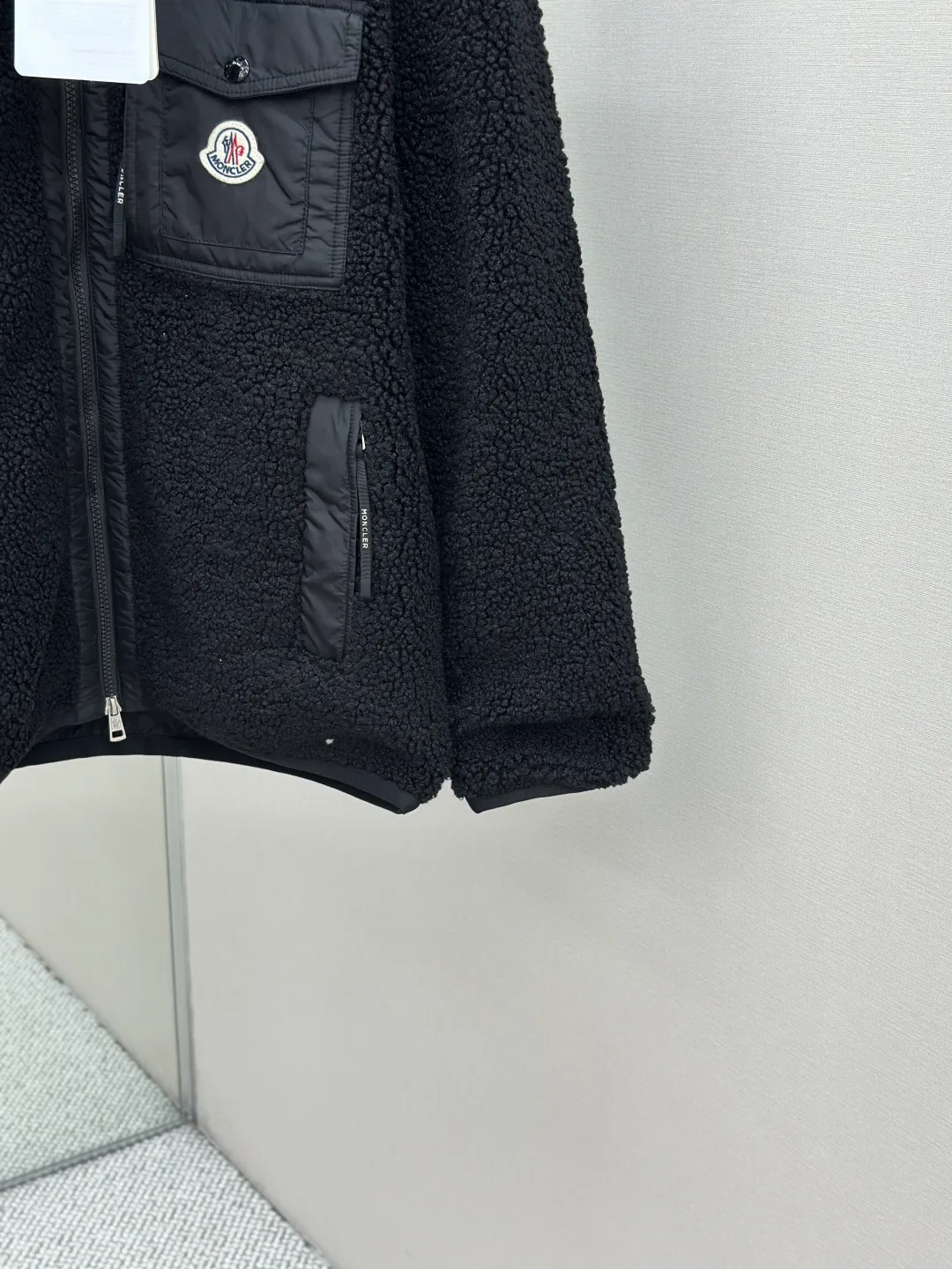 P620 MONCLER Emblem Suede Jacket Fabric Selection: Made from 100% polyester fiber, shearling fabric is woven through high-tech processing. The surface has a layer of fine, dense velvet, which feels very smooth when in contact with the skin and has good skin-friendliness. The suede surface can hold a layer of still air in place, forming a good thermal insulation layer and providing excellent warmth retention. Due to the hollow nature of the fiber, although it is warm, it does not hinder the overall lightness of the quality. Details: The neckline, front placket, side pockets, and chest patch pockets are all embellished with nylon fabrics of the same color, creating a visual sense of hierarchy. Decorated with elastic cuffs and hem, it balances practicality and beauty. Accessories: Customized zipper pendant Customized badge Customized pocket snap SIZE: S M L XL