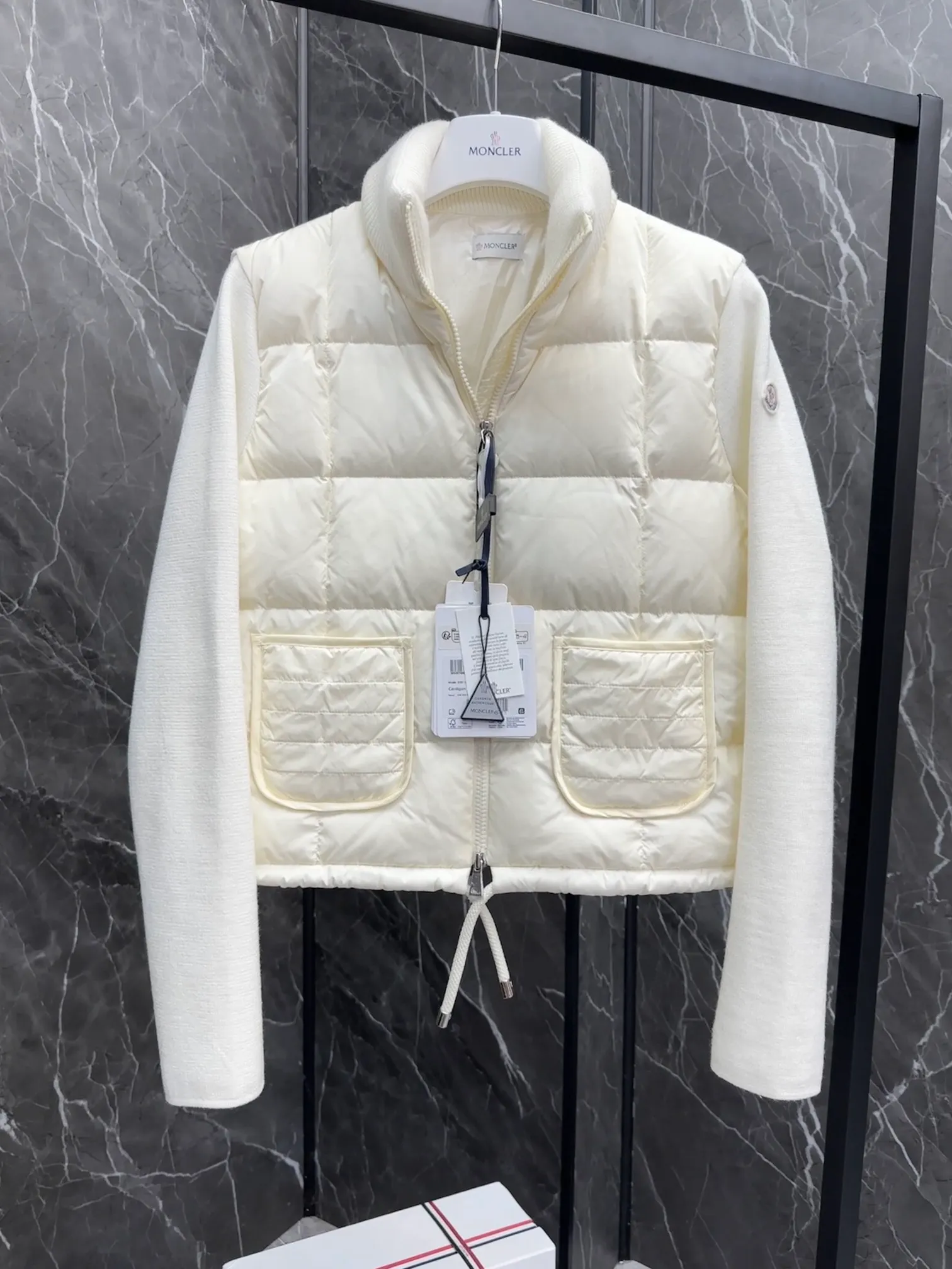 P600 New in Down ⬆️Moncler women’s padded wool zipper cardigan. This women’s wool cardigan is filled with down and can be styled in a variety of ways depending on the weather. (⚠️ Made of real wool, it will be slightly prickly when worn close to the body. It is recommended to match it with an inner layer. Fairies who are more concerned about it should not place an order.) This cardigan is made of wool and is filled with down on the front, back and collar. Lightweight knitted piece with a high collar and zip style. Details •Made from fine merino wool •Longue saison lining •Down filling at front, back and collar •Punto Milano stitching •14 stitches •Zip closure •Patch pockets •Drawstring hem Size: 1-4 Off-White Black L258031