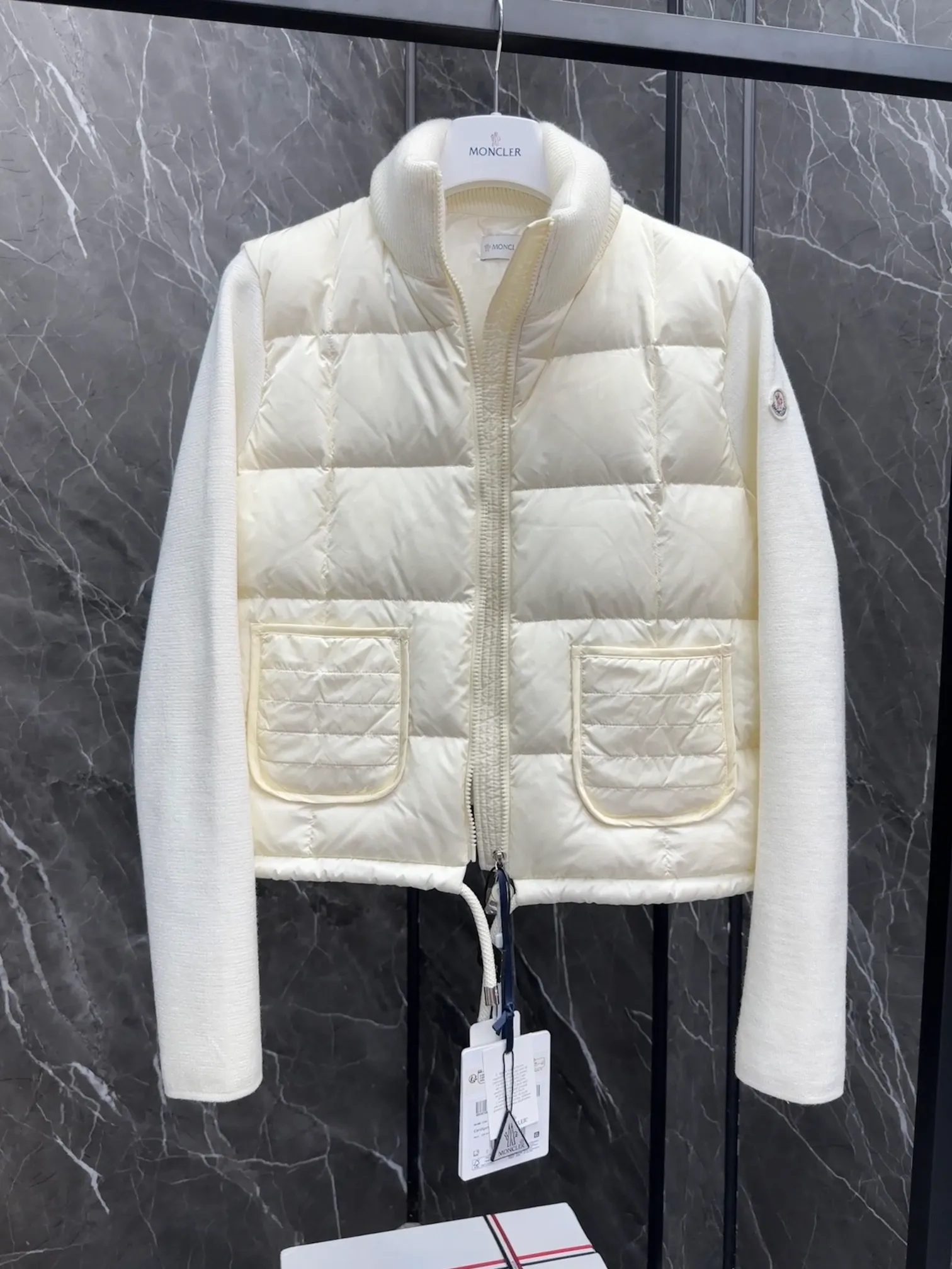 P600 New in Down ⬆️Moncler women’s padded wool zipper cardigan. This women’s wool cardigan is filled with down and can be styled in a variety of ways depending on the weather. (⚠️ Made of real wool, it will be slightly prickly when worn close to the body. It is recommended to match it with an inner layer. Fairies who are more concerned about it should not place an order.) This cardigan is made of wool and is filled with down on the front, back and collar. Lightweight knitted piece with a high collar and zip style. Details •Made from fine merino wool •Longue saison lining •Down filling at front, back and collar •Punto Milano stitching •14 stitches •Zip closure •Patch pockets •Drawstring hem Size: 1-4 Off-White Black L258031