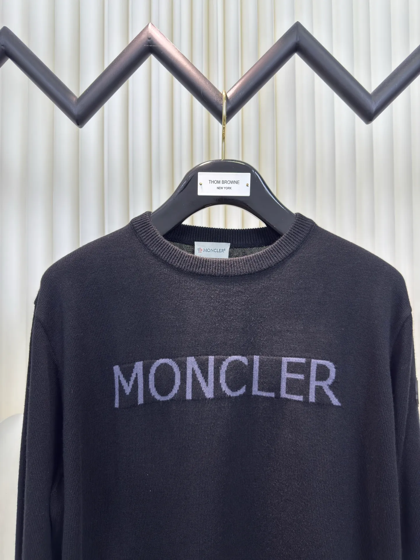 P440 MONCLER jacquard crew neck sweater is made of wool blended fabric, mainly 95% wool, combined with 4% nylon and 1% spandex. The main body of wool ensures the warmth and comfort of the clothing. The addition of a small amount of nylon and spandex significantly improves the elasticity and wear resistance. The ribbed decorative parts are made of 100% wool, which further enhances the overall texture.  Through the high needle count and fine gauge loom, combined with the orderly direction of the internal yarn, the floating threads are cleverly woven and stored, with almost no unnecessary thread mess. The color switching of each group of letters is synchronized with the knitting needles in milliseconds, forming a delicate letter LOGO jacquard decoration on the chest. Size S M L XL