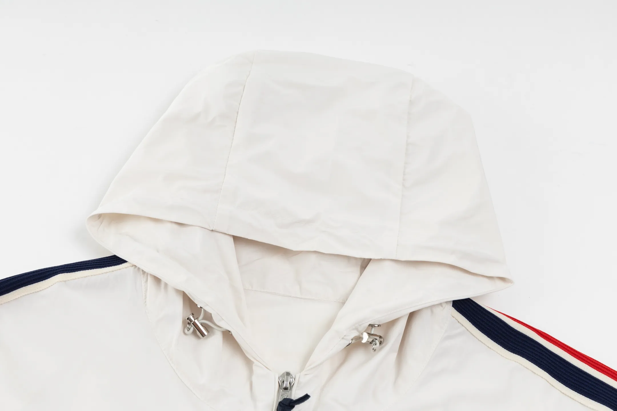 P550 Exclusive supply] Moncler Webbing Armband Lightweight Jacket (off-white) The fabric is made of 100% polyester fiber to create a tough protective outer layer. It is known for its excellent tear resistance and wear resistance. It can quickly return to flatness during wearing and maintain the crisp and stylish appearance of the clothing for a long time. At the same time, it is not easy to deform after being washed for a long time. Decorative edging in two different colors has been added to the center section of the sleeves. This design element not only adds visual highlights to the clothing, making it more fashionable and unique, the webbing is precisely positioned along the specified contours from the cuffs to the seam of the collar to ensure symmetry and overall smoothness. Before actual sewing, use very fine basting stitches for pre-fixing. This step is crucial to prevent the webbing from slipping, twisting, or wrinkling during sewing and ensuring that the final stitch is straight and perfect. Size:1/2/3/4