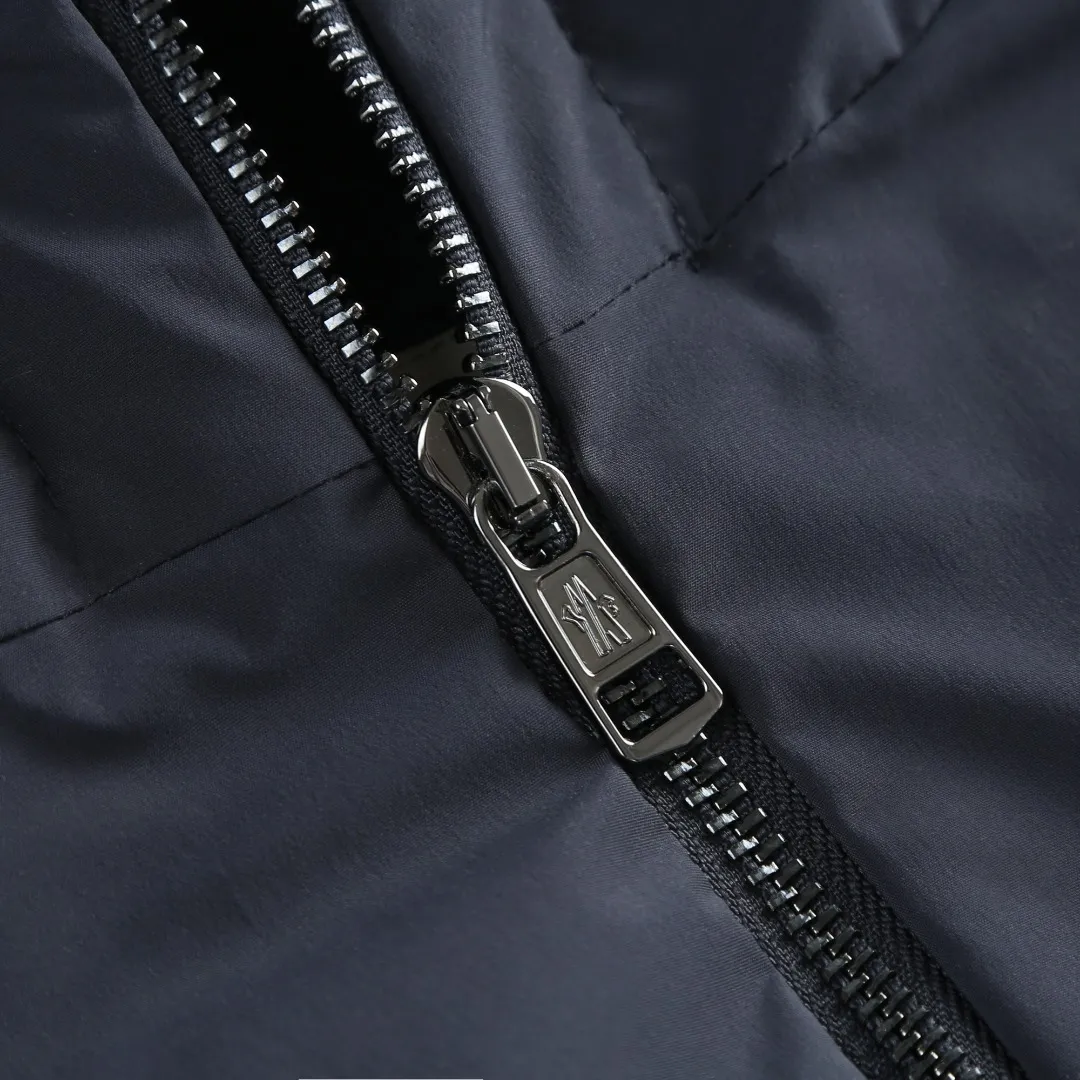 P860 MONCLER hooded jacket-style down jacket is made of 100% polyester fiber. After microfiberization treatment, the individual fibers become extremely fine, which greatly increases the fiber surface area, making the fabric soft and smooth, and the touch is close to natural fibers. The high-density textile method makes the structure tight, thus giving it a certain degree of wrinkle resistance, windproof warmth and wear resistance.  Lining selection: High-density lining fabric made of ultra-fine denier, 0.08mm thickness to avoid increasing the overall weight and making it smooth to wear. The high-density woven structure forms a wind resistance layer to protect the thermal efficiency of the thermal layer from loss. It can also withstand the expansion pressure of down and prevent deformation and damage after long-term use.  High-quality filling: 90 white duck down is selected, with a weight of 200g, ensuring excellent thermal insulation performance. After strict screening and treatment, the velvet is not easy to be drilled, ensuring durability. Details: The leather flap pocket on the chest is matched with a pebbled leather flap + matte metal buckle. It is low-key and exudes nobility. The hidden adjustment rope gives a sense of sophistication when you raise your hand. The "ID card" is directly embedded on the black satin inner patch pocket! Silver snaps + red, white and blue webbing, low-key yet exuding a sense of luxury, both visually and tactilely smooth.  Accessories: one-to-one customized buttons, one-to-one customized hem drawstring buckle, one-to-one customized phoenix eyes, one-to-one customized zipper pendant SIZE: 1 2 3 4