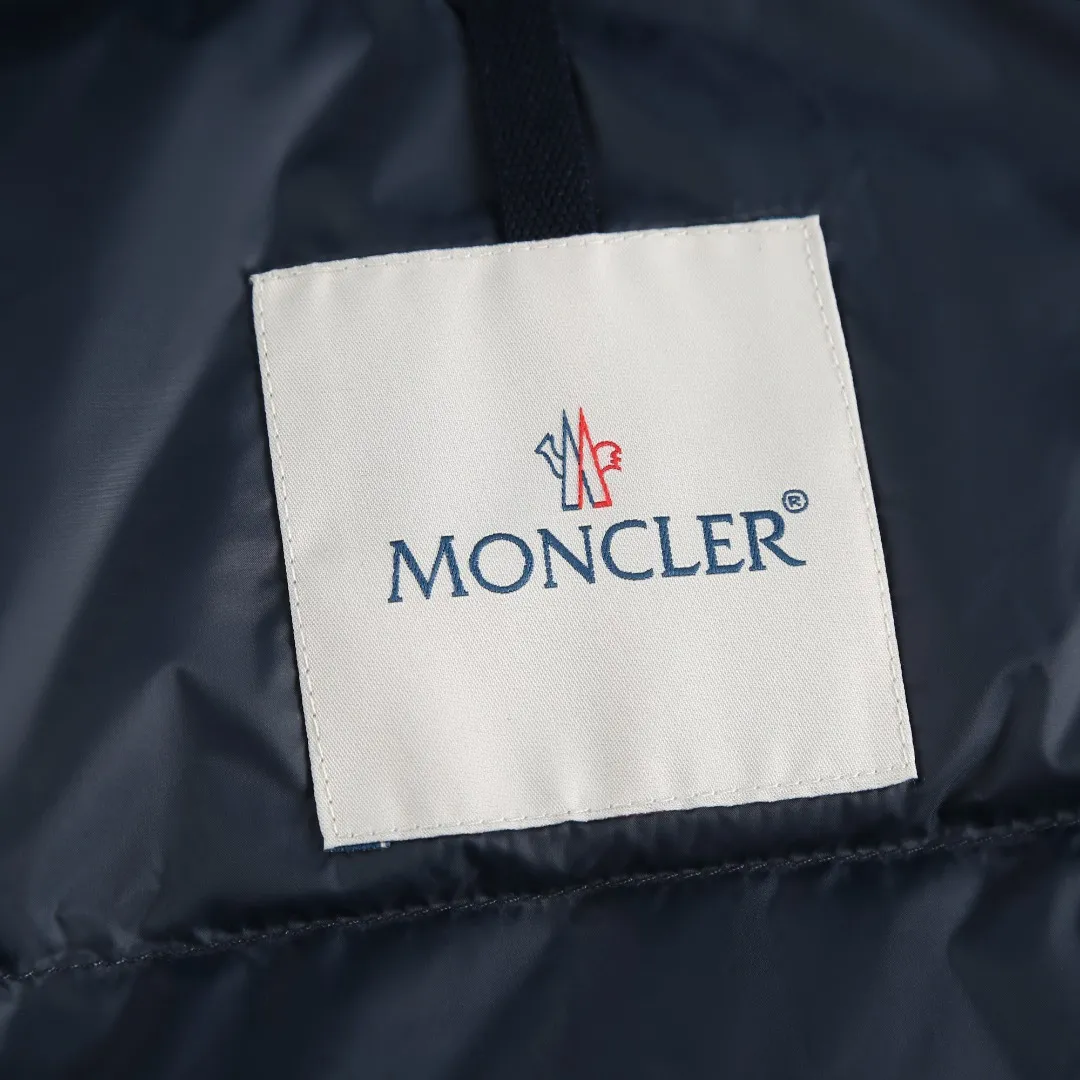 P860 MONCLER hooded jacket-style down jacket is made of 100% polyester fiber. After microfiberization treatment, the individual fibers become extremely fine, which greatly increases the fiber surface area, making the fabric soft and smooth, and the touch is close to natural fibers. The high-density textile method makes the structure tight, thus giving it a certain degree of wrinkle resistance, windproof warmth and wear resistance.  Lining selection: High-density lining fabric made of ultra-fine denier, 0.08mm thickness to avoid increasing the overall weight and making it smooth to wear. The high-density woven structure forms a wind resistance layer to protect the thermal efficiency of the thermal layer from loss. It can also withstand the expansion pressure of down and prevent deformation and damage after long-term use.  High-quality filling: 90 white duck down is selected, with a weight of 200g, ensuring excellent thermal insulation performance. After strict screening and treatment, the velvet is not easy to be drilled, ensuring durability. Details: The leather flap pocket on the chest is matched with a pebbled leather flap + matte metal buckle. It is low-key and exudes nobility. The hidden adjustment rope gives a sense of sophistication when you raise your hand. The "ID card" is directly embedded on the black satin inner patch pocket! Silver snaps + red, white and blue webbing, low-key yet exuding a sense of luxury, both visually and tactilely smooth.  Accessories: one-to-one customized buttons, one-to-one customized hem drawstring buckle, one-to-one customized phoenix eyes, one-to-one customized zipper pendant SIZE: 1 2 3 4