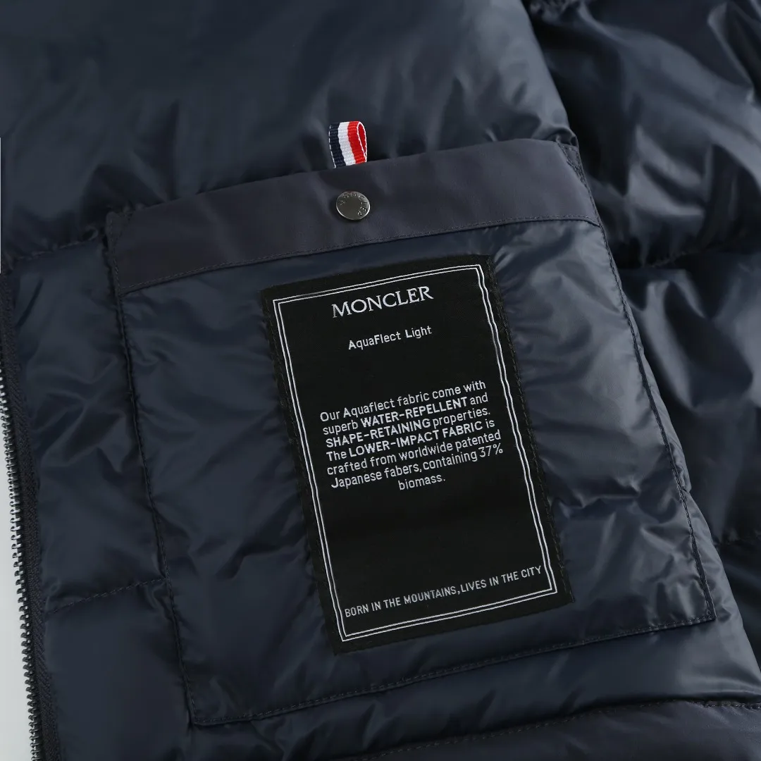 P860 MONCLER hooded jacket-style down jacket is made of 100% polyester fiber. After microfiberization treatment, the individual fibers become extremely fine, which greatly increases the fiber surface area, making the fabric soft and smooth, and the touch is close to natural fibers. The high-density textile method makes the structure tight, thus giving it a certain degree of wrinkle resistance, windproof warmth and wear resistance.  Lining selection: High-density lining fabric made of ultra-fine denier, 0.08mm thickness to avoid increasing the overall weight and making it smooth to wear. The high-density woven structure forms a wind resistance layer to protect the thermal efficiency of the thermal layer from loss. It can also withstand the expansion pressure of down and prevent deformation and damage after long-term use.  High-quality filling: 90 white duck down is selected, with a weight of 200g, ensuring excellent thermal insulation performance. After strict screening and treatment, the velvet is not easy to be drilled, ensuring durability. Details: The leather flap pocket on the chest is matched with a pebbled leather flap + matte metal buckle. It is low-key and exudes nobility. The hidden adjustment rope gives a sense of sophistication when you raise your hand. The "ID card" is directly embedded on the black satin inner patch pocket! Silver snaps + red, white and blue webbing, low-key yet exuding a sense of luxury, both visually and tactilely smooth.  Accessories: one-to-one customized buttons, one-to-one customized hem drawstring buckle, one-to-one customized phoenix eyes, one-to-one customized zipper pendant SIZE: 1 2 3 4