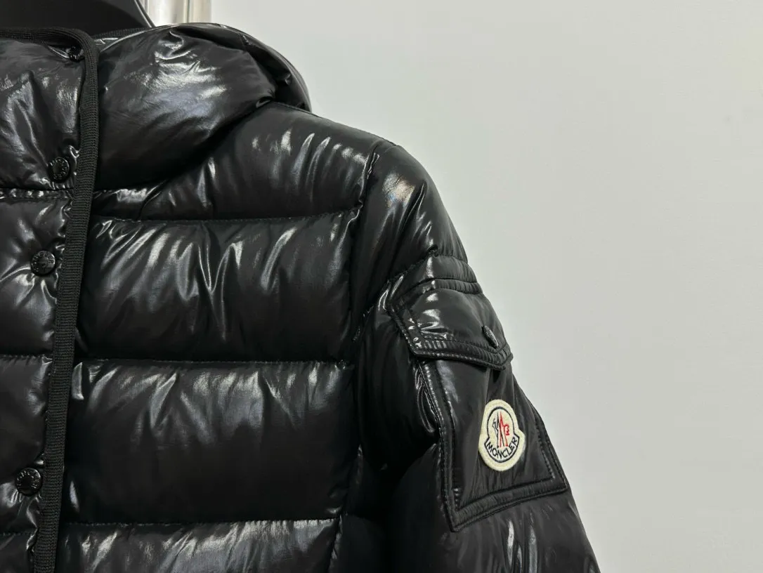 P860 [Moncler] Hooded, waisted women's short down jacket. The barante down jacket is made of glossy nylon fabric and is inspired by the 1970s. It adopts a waist design and presents an A-line silhouette, highlighting a feminine style. An adjustable hood and signature logo patch add finishing touches. Details · Made of lon laqué fabric · lon laqué lining · Filled with down · Adjustable hood · Zipper and snap closure · Suit pocket · Adjustable cuffs Size: 0/1/2/3