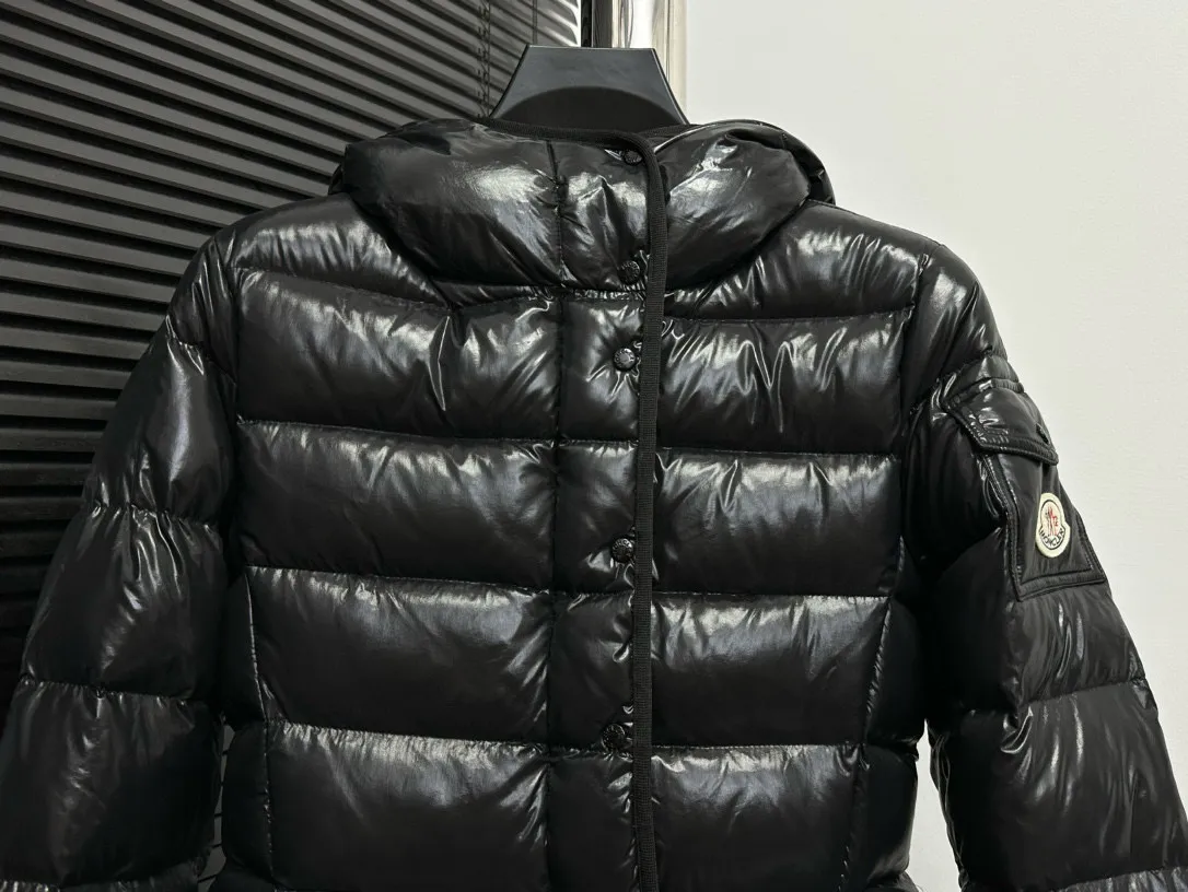 P860 [Moncler] Hooded, waisted women's short down jacket. The barante down jacket is made of glossy nylon fabric and is inspired by the 1970s. It adopts a waist design and presents an A-line silhouette, highlighting a feminine style. An adjustable hood and signature logo patch add finishing touches. Details · Made of lon laqué fabric · lon laqué lining · Filled with down · Adjustable hood · Zipper and snap closure · Suit pocket · Adjustable cuffs Size: 0/1/2/3