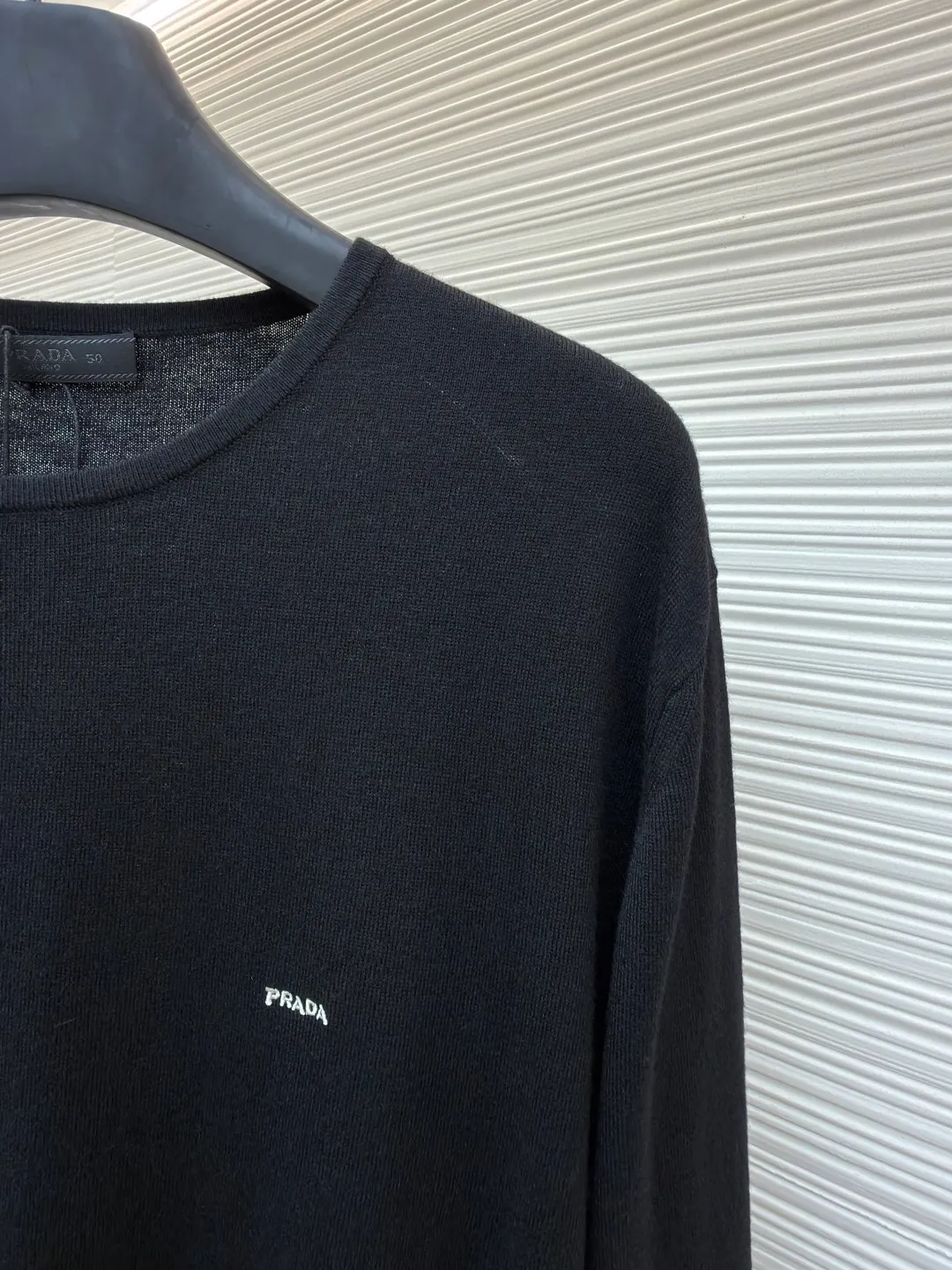 Prada Worsted Wool Long Sleeve ●Item No.: 1682330-A65 ●Material: Wool fabric ●Technology: Knitting ●Color: Black ●Version: Fitted version ●Weight: about 240 grams ●Size: S-M-L-XL ●Description: Made of fine worsted wool fiber, the sweater feels soft to the touch and is light and comfortable to wear. Wool fiber has good thermal insulation properties and is suitable for wearing in colder weather. The fiber length is moderate and free of impurities to ensure the quality and comfort of the garment. Knitted using a jersey technique, it forms the main body of the sweater. During the knitting process, the stitches must be kept even to avoid problems such as missing stitches and broken threads. After knitting is completed, the sweater needs to be ironed to make it smooth and crisp and improve the overall texture. Rib knitting technology is used for splicing to increase elasticity and fit, making the cuffs and hem tighter and more stylish. The raglan part needs to be carefully spliced ​​with the main part to ensure smooth and natural shoulder lines. The overall wiring is straight and delicate, the fabric is comfortable and soft, and the color is consistent without color difference. It can be matched with the same style to create a fashionable look and control various occasions. Customized accessories, complete with three standards, same style for men and women!