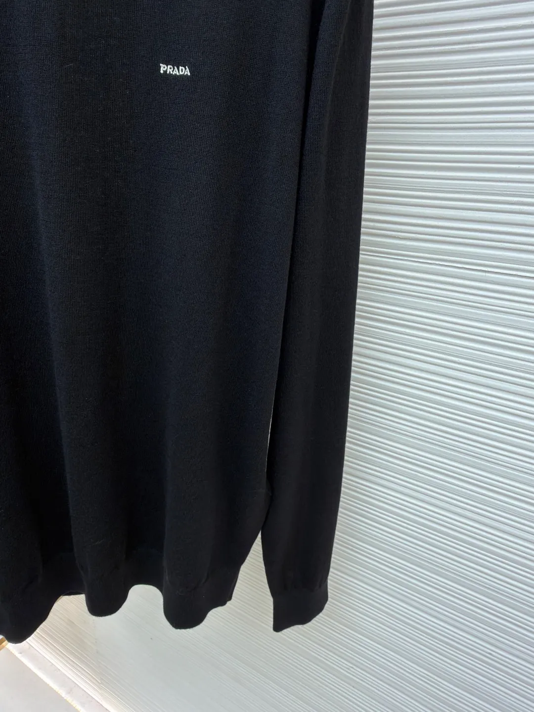 Prada Worsted Wool Long Sleeve ●Item No.: 1682330-A65 ●Material: Wool fabric ●Technology: Knitting ●Color: Black ●Version: Fitted version ●Weight: about 240 grams ●Size: S-M-L-XL ●Description: Made of fine worsted wool fiber, the sweater feels soft to the touch and is light and comfortable to wear. Wool fiber has good thermal insulation properties and is suitable for wearing in colder weather. The fiber length is moderate and free of impurities to ensure the quality and comfort of the garment. Knitted using a jersey technique, it forms the main body of the sweater. During the knitting process, the stitches must be kept even to avoid problems such as missing stitches and broken threads. After knitting is completed, the sweater needs to be ironed to make it smooth and crisp and improve the overall texture. Rib knitting technology is used for splicing to increase elasticity and fit, making the cuffs and hem tighter and more stylish. The raglan part needs to be carefully spliced ​​with the main part to ensure smooth and natural shoulder lines. The overall wiring is straight and delicate, the fabric is comfortable and soft, and the color is consistent without color difference. It can be matched with the same style to create a fashionable look and control various occasions. Customized accessories, complete with three standards, same style for men and women!
