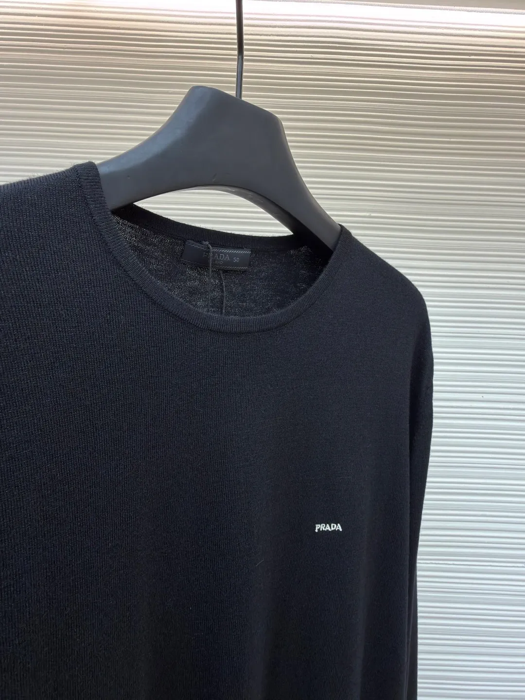 Prada Worsted Wool Long Sleeve ●Item No.: 1682330-A65 ●Material: Wool fabric ●Technology: Knitting ●Color: Black ●Version: Fitted version ●Weight: about 240 grams ●Size: S-M-L-XL ●Description: Made of fine worsted wool fiber, the sweater feels soft to the touch and is light and comfortable to wear. Wool fiber has good thermal insulation properties and is suitable for wearing in colder weather. The fiber length is moderate and free of impurities to ensure the quality and comfort of the garment. Knitted using a jersey technique, it forms the main body of the sweater. During the knitting process, the stitches must be kept even to avoid problems such as missing stitches and broken threads. After knitting is completed, the sweater needs to be ironed to make it smooth and crisp and improve the overall texture. Rib knitting technology is used for splicing to increase elasticity and fit, making the cuffs and hem tighter and more stylish. The raglan part needs to be carefully spliced ​​with the main part to ensure smooth and natural shoulder lines. The overall wiring is straight and delicate, the fabric is comfortable and soft, and the color is consistent without color difference. It can be matched with the same style to create a fashionable look and control various occasions. Customized accessories, complete with three standards, same style for men and women!