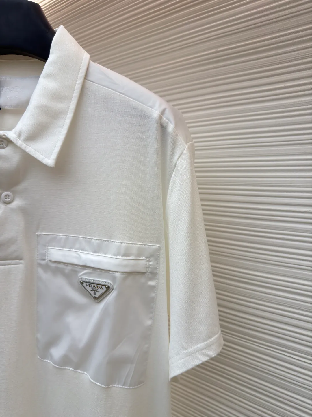Prada Triangle Pocket Polo Shirt ●Original version: Purchased and developed at 9050 ●Item number: 1682394-A25 ●Fabric: mercerized grosgrain fabric ●Technology: needle and shuttle splicing ●Color: white ●Version: fitted version ●Weight: about 215 grams ●Size: S-M-L-XL ●Description: Customized mercerized grosgrain fabric, smooth and delicate, comfortable and close to the skin, classic black tone exudes an innate sense of luxury and is devouring with warmth The iconic triangular logo embellishes the chest, highlighting the elegance and nobility of the brand. The exquisite zipper pocket design is cleverly integrated, making the Polo shirt instantly rejuvenated. The perfect collision of simplicity and style. A versatile artifact in the wardrobe, the "Prada triangle mark" is positioned using an imported special machine infrared to position it more accurately and firmly. Needle and shuttle stitching technology can make full use of the respective advantages of knitted fabrics and woven fabrics. By choosing the appropriate sewing process and stitches, it can ensure that the splicing parts are strong and beautiful. The template machine opens the bag. The preset template guides the position, shape and size of the bag opening. The accuracy ensures the quality of the bag opening effect. The overall wiring is straight and delicate, the fabric is comfortable and soft, and the color is consistent without color difference. It can be matched with the same style to create a fashionable look and control various occasions. Customized accessories, complete with three standards, same style for men and women!