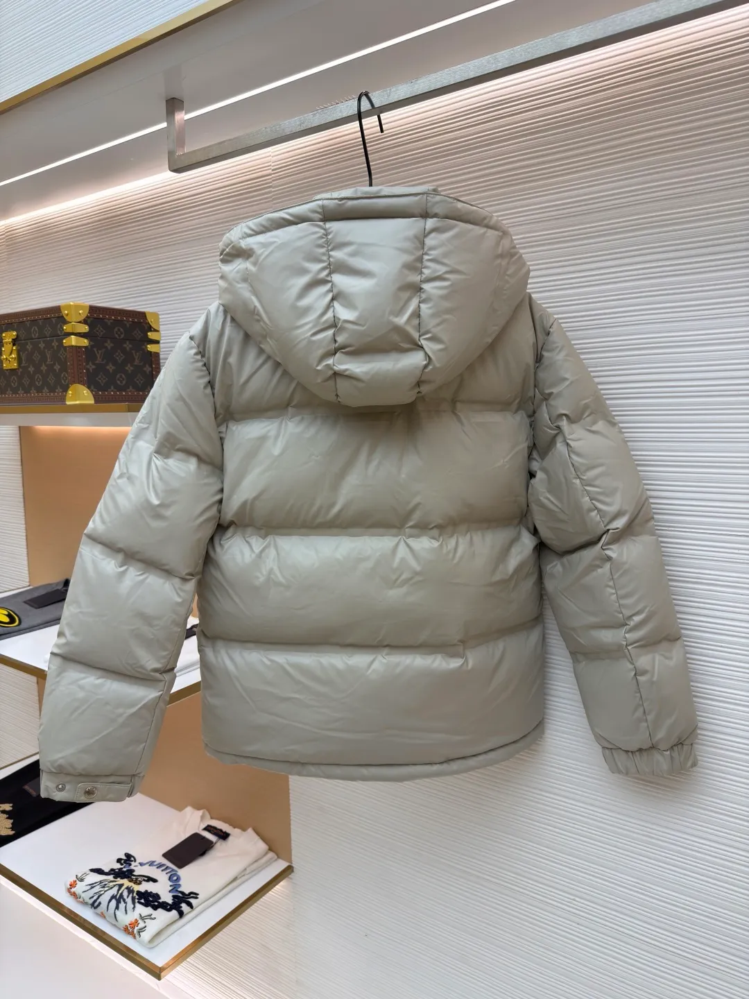 Prada solid color down jacket with removable hood ●Item number: 1682018-D15 ●Fabric: white duck down fabric ●Technology: mechanical down filling ●Color: light khaki gray ●Version: fitted version ●Weight: about 1070 grams ●Size: 48-50-52-54-56 ●Description: This Prada down jacket is made of regenerated nylon fabric, which is treated with high-density weaving and Teflon coating. It is waterproof and wrinkle-resistant and has a matte soft texture. The filling is made of 90% white duck down, and the down is locked in zones through 65-degree diagonal quilting technology. The stitch length is precisely controlled at 3 stitches/cm to avoid down fleece and give the body three-dimensional bulk. The detachable hood is fixed with metal snaps, and the bevel stitching on the neckline improves the fit; the triangle logo on the chest is presented in metal relief, seamlessly connecting with the same-color stitching on the body. The cuffs and hem are equipped with elastic ribs, the side invisible zipper pockets are hot-melt bonded, and the brand's customized hardware accessories are used in every detail, taking into account functionality and luxury texture. The overall wiring is straight and delicate, the fabric is comfortable and soft, and the color is consistent without color difference. It can be matched with the same style to create a fashionable look and control various occasions. Customized accessories, complete with three standards, same style for men and women!