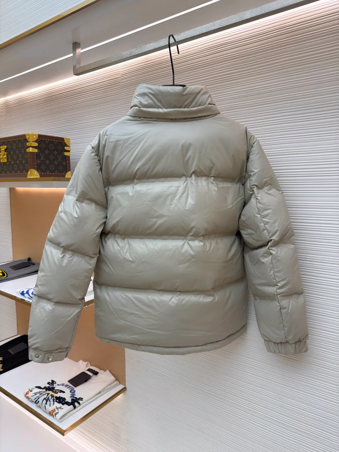 Prada solid color down jacket with removable hood ●Item number: 1682018-D15 ●Fabric: white duck down fabric ●Technology: mechanical down filling ●Color: light khaki gray ●Version: fitted version ●Weight: about 1070 grams ●Size: 48-50-52-54-56 ●Description: This Prada down jacket is made of regenerated nylon fabric, which is treated with high-density weaving and Teflon coating. It is waterproof and wrinkle-resistant and has a matte soft texture. The filling is made of 90% white duck down, and the down is locked in zones through 65-degree diagonal quilting technology. The stitch length is precisely controlled at 3 stitches/cm to avoid down fleece and give the body three-dimensional bulk. The detachable hood is fixed with metal snaps, and the bevel stitching on the neckline improves the fit; the triangle logo on the chest is presented in metal relief, seamlessly connecting with the same-color stitching on the body. The cuffs and hem are equipped with elastic ribs, the side invisible zipper pockets are hot-melt bonded, and the brand's customized hardware accessories are used in every detail, taking into account functionality and luxury texture. The overall wiring is straight and delicate, the fabric is comfortable and soft, and the color is consistent without color difference. It can be matched with the same style to create a fashionable look and control various occasions. Customized accessories, complete with three standards, same style for men and women!