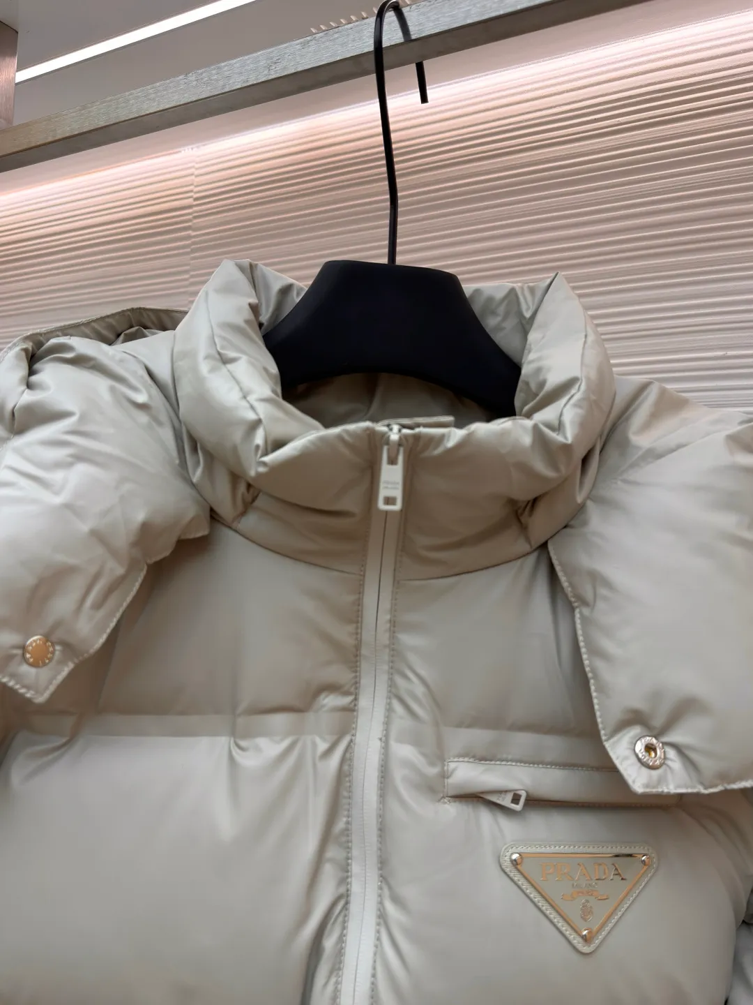 Prada solid color down jacket with removable hood ●Item number: 1682018-D15 ●Fabric: white duck down fabric ●Technology: mechanical down filling ●Color: light khaki gray ●Version: fitted version ●Weight: about 1070 grams ●Size: 48-50-52-54-56 ●Description: This Prada down jacket is made of regenerated nylon fabric, which is treated with high-density weaving and Teflon coating. It is waterproof and wrinkle-resistant and has a matte soft texture. The filling is made of 90% white duck down, and the down is locked in zones through 65-degree diagonal quilting technology. The stitch length is precisely controlled at 3 stitches/cm to avoid down fleece and give the body three-dimensional bulk. The detachable hood is fixed with metal snaps, and the bevel stitching on the neckline improves the fit; the triangle logo on the chest is presented in metal relief, seamlessly connecting with the same-color stitching on the body. The cuffs and hem are equipped with elastic ribs, the side invisible zipper pockets are hot-melt bonded, and the brand's customized hardware accessories are used in every detail, taking into account functionality and luxury texture. The overall wiring is straight and delicate, the fabric is comfortable and soft, and the color is consistent without color difference. It can be matched with the same style to create a fashionable look and control various occasions. Customized accessories, complete with three standards, same style for men and women!