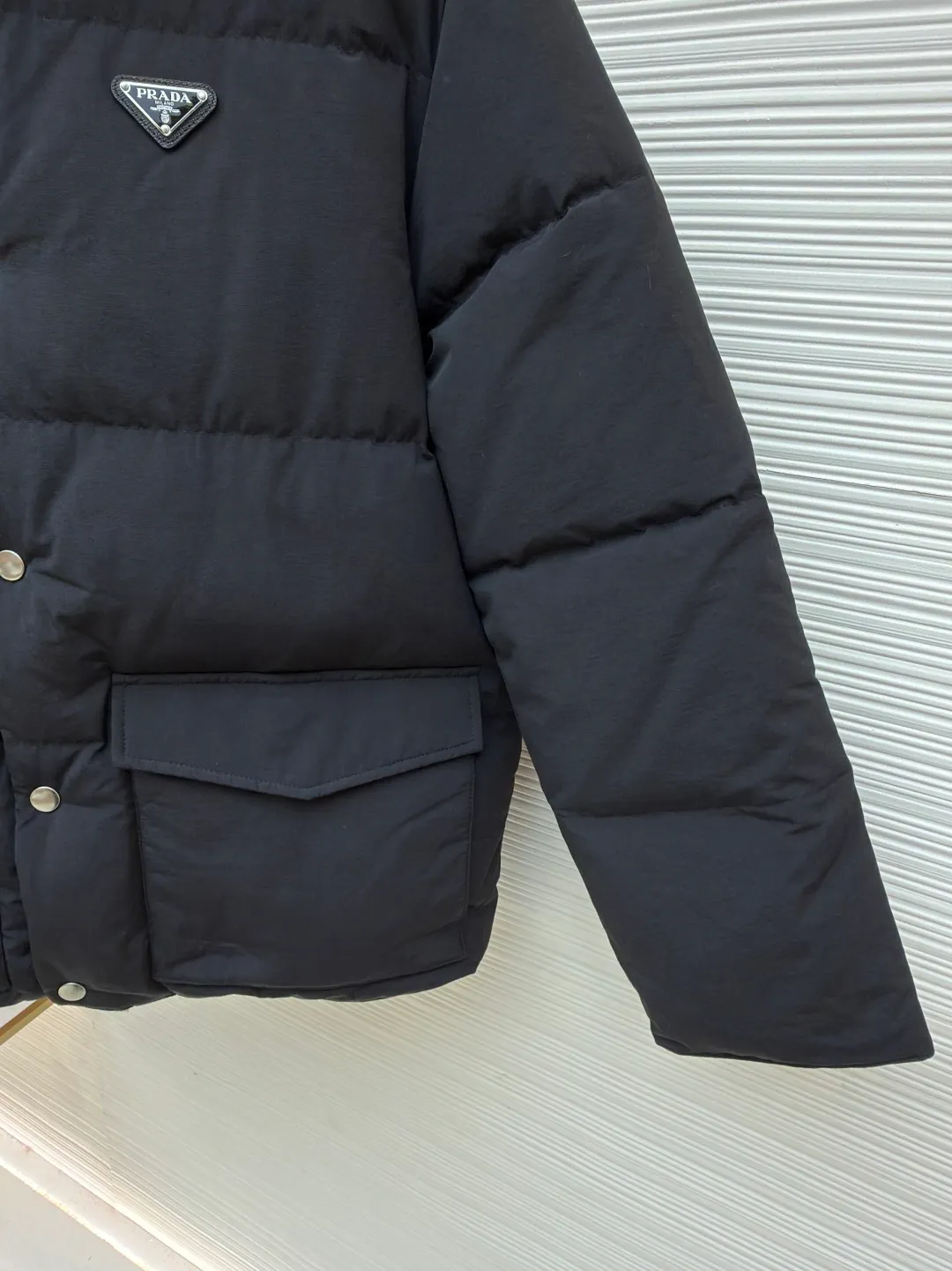 Prada triangle logo basic down jacket ●Original version: purchased and developed by 23122 ●Item number: 1681859-D15 ●Fabric: white duck down fabric ●Technology: mechanical down filling ●Color: black ●Version: fitted version ●Weight: about 1060 grams ●Size: S-M-L-XL ●Description: It is made of extremely fine nylon yarn and is woven in a high-density manner. The number of yarns per unit area is large, and the gaps between the yarns are very small, which can effectively block the penetration of cold wind. The fine weave keeps it lightweight and soft to the touch, physically restricting the lightweight down fibers from slipping through the gaps. Nylon fiber itself has good wear resistance and is not easy to snag, which significantly extends its service life and can easily cope with the needs of multiple scenarios. The lining is made of high-density weaving of 100% polyester fiber, with a thickness of 0.08mm to avoid increasing the overall weight and making it smooth to wear. The high-density weaving structure forms a wind resistance layer to protect the thermal efficiency of the thermal layer from loss. It can withstand the expansion pressure of down and prevent deformation and damage after long-term use. Each buckle is suspended independently, and in the carefully controlled current and solution, a 360-degree uniform coating without dead ends is achieved, which has stronger wear resistance and corrosion resistance. The interior is filled with 90% of the new national standard white duck down, with a filling capacity of up to 280 grams. The down is full and fluffy, and has excellent temperature locking performance. It is light and weightless, but can withstand the cold wind, making walking in winter as smooth as spring. The overall wiring is straight and delicate, the fabric is comfortable and soft, and the color is consistent without color difference. It can be matched with the same style to create a fashionable look and control various occasions. Customized accessories, complete with three standards, same style for men and women!