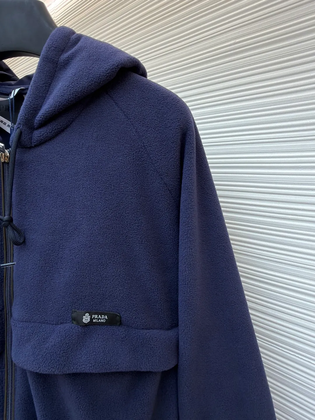 Prada hooded drawstring fabric short jacket ●Original version: Purchased and developed for 22300 ●Item number: 1682436-B25 ●Fabric: polar fleece fabric ●Technology: hand-sewn label production ●Color: navy blue ●Version: fitted version ●Weight: about 720 grams ●Size: 46-48-50-52 ●Description: This PRADA hooded drawstring fabric short jacket is made of high-quality fabric as the core material. It is first treated with an enzyme washing process to make the fabric soft and skin-friendly. It also enhances the wrinkle resistance and color fastness of the fabric, making the navy blue tone more textured and not easy to fade. The body is designed with a short cut and is equipped with a hooded drawstring structure. The drawstring is treated with reinforced stitching to ensure smooth adjustment and durability. The shoulders are made of raglan sleeves, which improves the freedom of movement of the wearer. Flat seams are used at the splicing between the pockets and the body, and the stitching is neat and precise. The brand logo is fixed through hand-sewing technology, and the stitching is even and firm, retaining the brand texture. The entire garment is stitched with high-tenacity stitches of the same color. The measurement error of 1~3cm is within the normal range. The overall craftsmanship takes into account both functionality and luxury details. Hand washing is recommended to maintain the integrity of the fabric and craftsmanship. The overall wiring is straight and delicate, the fabric is comfortable and soft, and the color is consistent without color difference. It can be matched with the same style to create a fashionable look and control various occasions. Customized accessories, complete with three standards, same style for men and women!