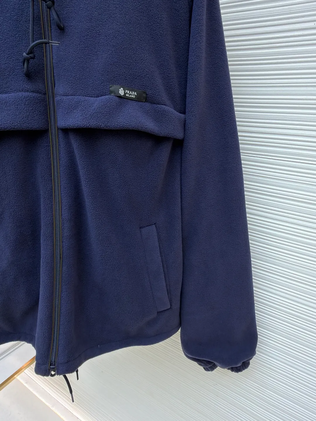 Prada hooded drawstring fabric short jacket ●Original version: Purchased and developed for 22300 ●Item number: 1682436-B25 ●Fabric: polar fleece fabric ●Technology: hand-sewn label production ●Color: navy blue ●Version: fitted version ●Weight: about 720 grams ●Size: 46-48-50-52 ●Description: This PRADA hooded drawstring fabric short jacket is made of high-quality fabric as the core material. It is first treated with an enzyme washing process to make the fabric soft and skin-friendly. It also enhances the wrinkle resistance and color fastness of the fabric, making the navy blue tone more textured and not easy to fade. The body is designed with a short cut and is equipped with a hooded drawstring structure. The drawstring is treated with reinforced stitching to ensure smooth adjustment and durability. The shoulders are made of raglan sleeves, which improves the freedom of movement of the wearer. Flat seams are used at the splicing between the pockets and the body, and the stitching is neat and precise. The brand logo is fixed through hand-sewing technology, and the stitching is even and firm, retaining the brand texture. The entire garment is stitched with high-tenacity stitches of the same color. The measurement error of 1~3cm is within the normal range. The overall craftsmanship takes into account both functionality and luxury details. Hand washing is recommended to maintain the integrity of the fabric and craftsmanship. The overall wiring is straight and delicate, the fabric is comfortable and soft, and the color is consistent without color difference. It can be matched with the same style to create a fashionable look and control various occasions. Customized accessories, complete with three standards, same style for men and women!