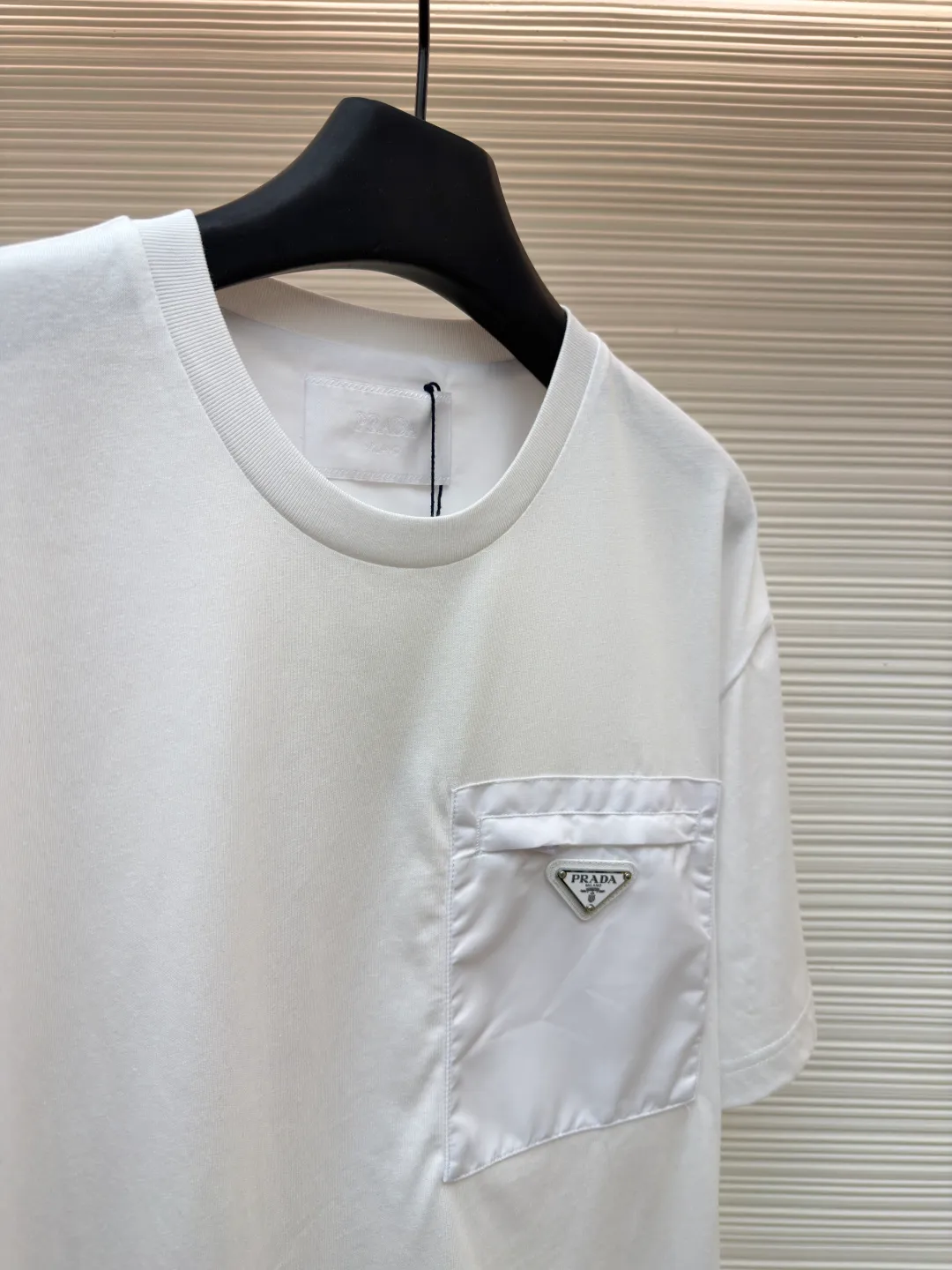 Prada Triangle Logo Pocket Short Sleeves ●Original version: Purchased and developed for 7000 ●Item number: 1682395-A05 ●Fabric: High-elastic jersey fabric ●Technology: Needle and shuttle splicing ●Color: white ●Version: Fitted version ●Weight: about 230 grams ●Size: S-M-L-XL ●Description: Customized high-elastic jersey material, delicate and soft, comfortable and close to the skin, a touch of simple white, as pure as ever, elegant and self-evident The iconic Prada triangle logo is embellished on the chest. It is integrated with Re-Nylon nylon fabric to decorate the square silhouette. Cross-disciplinary aesthetic grafting. The exquisite small pocket design highlights quality and style. It reveals a flexible and relaxed beauty. It is a picture of strolling in the city and deconstructs the attitude of the modern gentleman. The infrared positioning of the "Prada triangle mark" by an imported special machine is more precise and firm. Needle and shuttle stitching technology can make full use of the respective advantages of knitted fabrics and woven fabrics. By choosing the appropriate sewing process and stitches, it can ensure that the splicing parts are strong and beautiful. Template machine bag opening The preset template guides the position, shape and size of the bag opening. The accuracy ensures the quality of the bag opening effect. The overall wiring is straight and delicate, the fabric is comfortable and soft, and the color is consistent without color difference. It can be matched with the same style to create a fashionable look and control various occasions. Customized accessories, complete with three standards, same style for men and women!