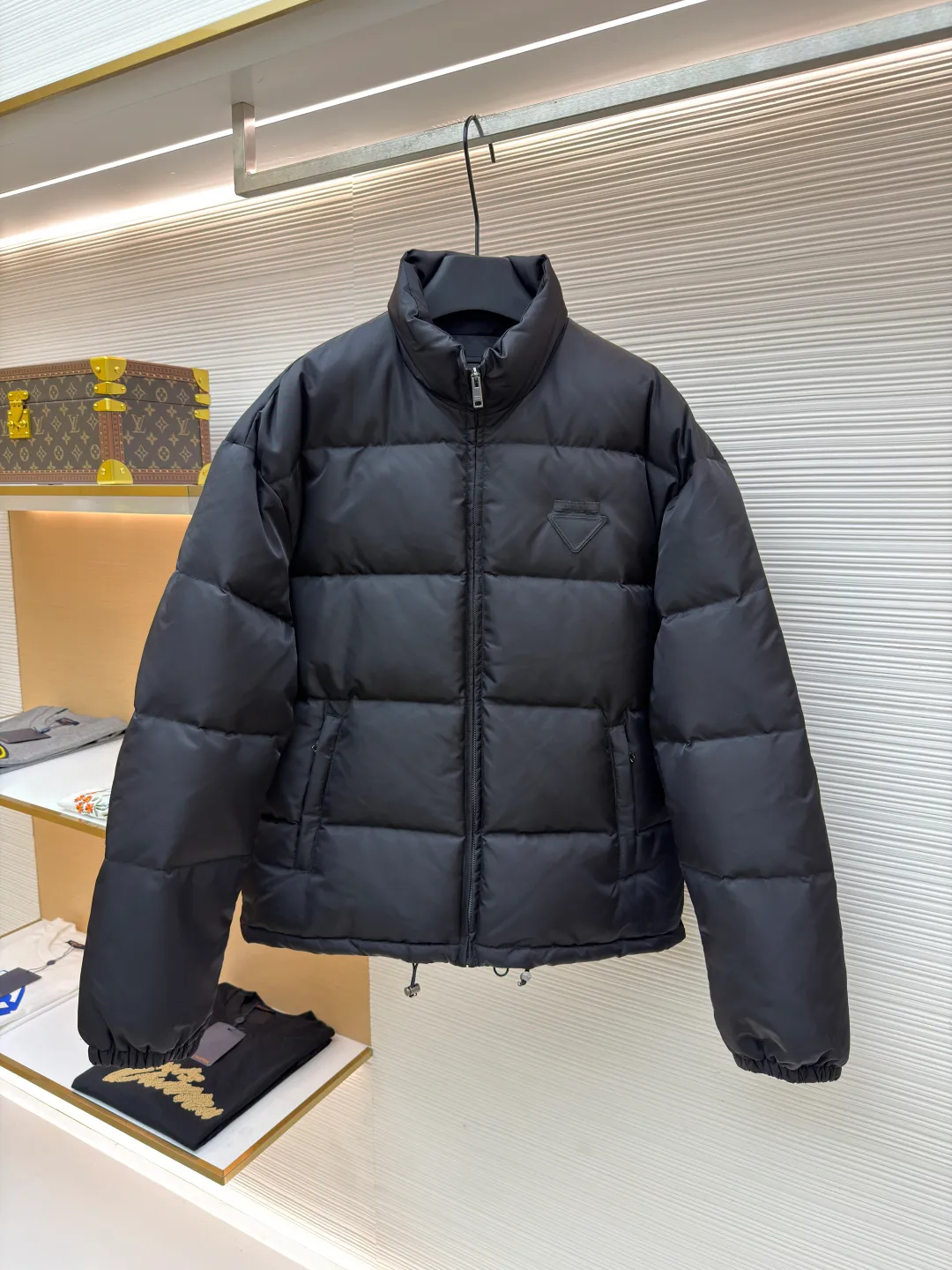 Prada nylon triangle down jacket ●Original version: Purchased and developed by 13557 ●Item number: 1681282-C95 ●Fabric: white duck down fabric ●Technology: mechanical down filling ●Color: black ●Version: fitted version ●Weight: about 1025 grams ●Size: S-M-L-XL ●Description: Made of high-count and high-density nylon woven fabric, it is a lightweight, strong and fine-textured advanced fabric. Its physical complexity lies in the fact that while achieving extreme lightweight, it provides excellent tear resistance and abrasion resistance through a dense fabric structure, solving the industry problem of light weight and durability that are often contradictory. Waterproof coating: This is not a simple film, but a microscopic functional polymer layer coated on the surface of the fabric after it is woven. Its complexity is reflected in its chemical properties: it can effectively reduce the surface tension of the fabric, making it impossible for water droplets to penetrate its fiber gaps, thereby forming a lotus leaf effect and achieving efficient waterproofing. At the same time, this coating usually has a certain degree of breathability, allowing moisture emitted by the body to escape and maintaining a comfortable internal microclimate. This is a precise balancing technology. The laser-burned triangle mark on the chest is the pinnacle of the complexity of the entire garment's craftsmanship. Laser burning is a non-contact precision processing technology. Using a laser beam of specific wavelength and energy, the fibers on the surface of the fabric are vaporized according to a preset digital path. The laser can accurately "carve" every detail of the logo without damaging the underlying fabric structure, with clear and sharp edges and a unique, slightly burning matte texture. This is completely different from traditional embroidery or offset printing. It is integrated with the fabric itself and cannot be peeled off. It also requires extremely high stability in process control - if the energy is slightly weaker, the pattern will be unclear, and if the energy is slightly stronger, it may penetrate the fabric. The core is filled with 90% pure white duck down. "90% pure white duck down" is an indicator that has been strictly sorted. The thermal insulation principle of down is that its three-dimensional velvet can hold a large amount of still air and form an efficient thermal insulation layer. To sum up, every part of this down jacket goes beyond basic functions and embodies full-link innovation and quality control from raw material selection, textile engineering, chemical processing to digital finishing. The overall wiring is straight and delicate, the fabric is comfortable and soft, and the color is consistent without color difference. It can be matched with the same style to create a fashionable look and control various occasions. Customized accessories, complete with three standards, same style for men and women!
