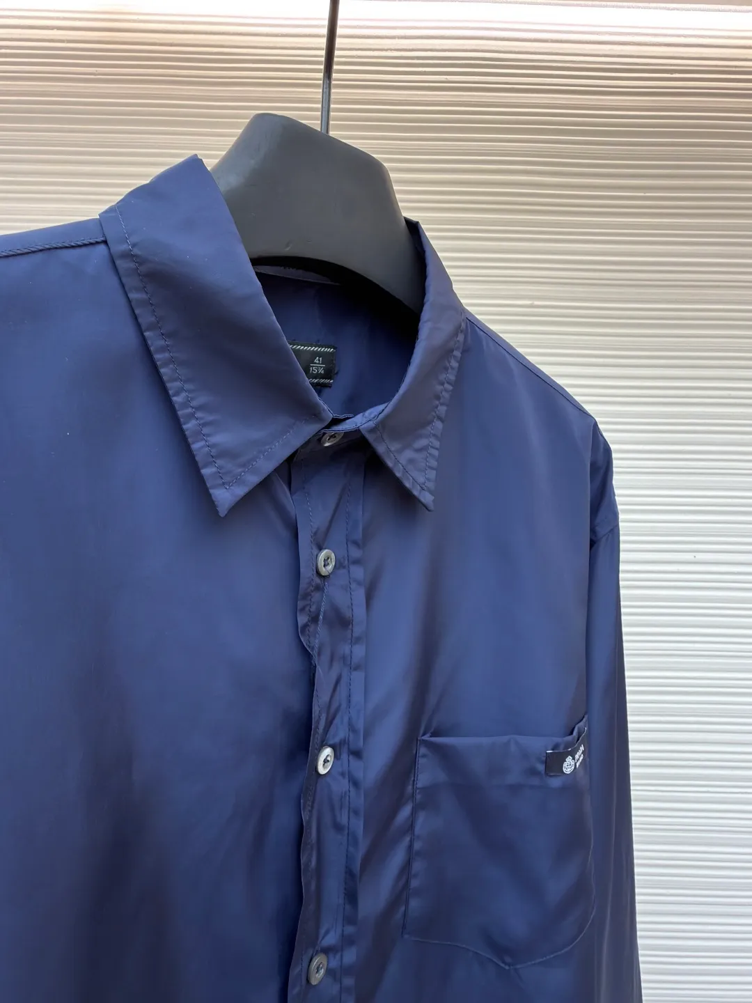 Prada triangle emblem label shirt ●Original version: Purchased and developed by 8100 ●Item number: 1682219-A75 ●Material: Regenerated nylon fabric ●Technology: Human body draping and production ●Color: blue ●Version: Fitted version ●Weight: about 180 grams ●Size: 39-40-41-42 ●Description: Custom-dyed regenerated nylon material feels like futuristic technology, light and tough, comfortable and skin-friendly Reconstructing the aesthetics of masculine power with deep sea blue tones. It has a mysterious and elegant aura. The Prada logo label is embellished on the chest patch pocket and complements the triangular logo on the back fabric to express the brand identity. The slightly wide shoulder line and curved hem form an architectural-level silhouette. The visual aristocratic gene, minimalism and luxury coexist, interpreting high-end fashion style. Silk double yarn interweaving processing technology uses nano-imprint technology to build honeycomb-shaped protrusions on the surface of the fabric, and then uses high temperature and high pressure to form covalent bonds between fluorine atoms and nylon fibers, forming a micro-matte film layer on the surface to prevent oil stains from reducing the waterproof performance. Three-dimensional tailoring of the human body returns to traditional craftsmanship through segmentation, folding, shrinking, and stretching techniques. The so-called slow work produces fine work, which is the respect for the material and the pursuit of feel. The workmanship is complicated and tedious, and the timeliness is slow. The side-turning buried clamping line process is used to make it smooth, neat, and tidy. The overall wiring is straight and delicate, the fabric is comfortable and soft, and the color is consistent without color difference. It can be matched with the same style to create a fashionable look and control various occasions. Customized accessories, complete with three standards, same style for men and women!