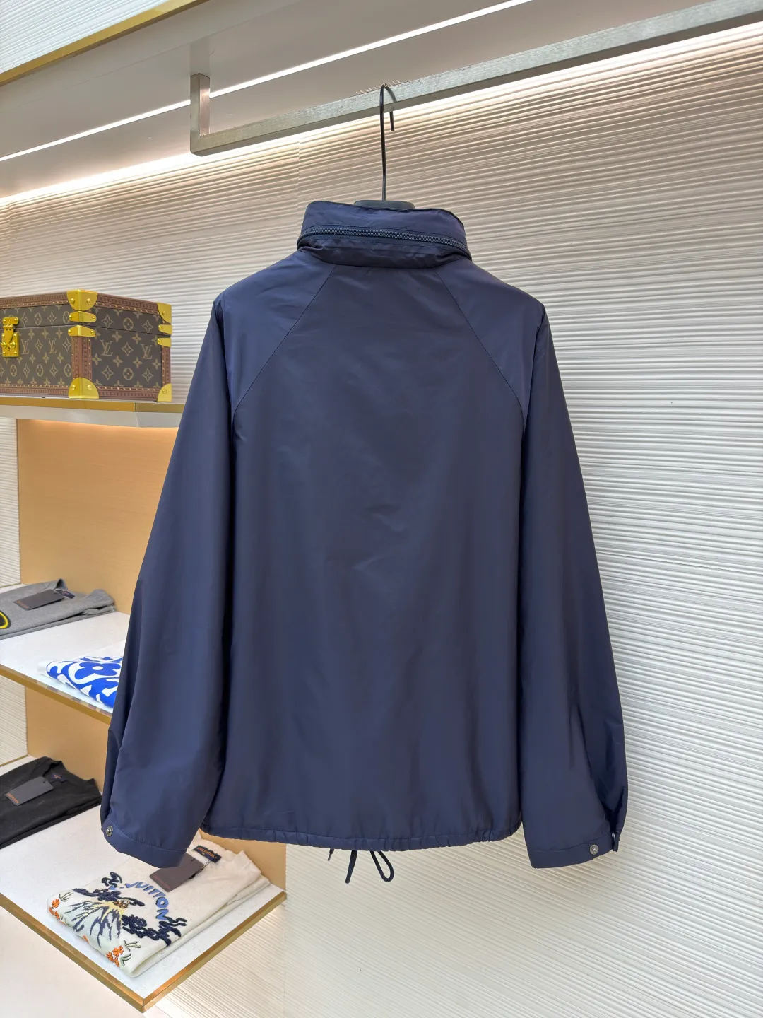 Prada Regenerated Nylon Fleece Jacket ●Original version: Purchased and developed by 12048 ●Item number: 1682331-B70 ●Fabric: Regenerated nylon fabric ●Technology: Made on positioning cutting machine ●Color: Navy blue ●Version: Fitted version ●Weight: about 585 grams ●Size: S-M-L-XL ●Description: High-density yarn is made by melt spinning through a special process. The yarn has been stretched and twisted through multiple processes to give the fabric the stiffness and wrinkle resistance that are comparable to those of native materials, while retaining a light and drapey wearing experience. The surface of the fabric is treated with an environmentally friendly coating process to form a micro-waterproof film layer, which is both windproof and breathable. The main raw material is polyester fiber blended wool raw material which is cleaned and pre-treated to remove impurities. After the yarn is woven into fabric through a loom, it is brushed, that is, the surface of the fiber is fluffed through mechanical brushing to form fluff. Then the shaking process is carried out, and the fabric is shaken under high temperature and humid conditions, so that the fibers form small spherical particles to increase the thermal insulation performance. The shoulder splicing uses twill sewing technology, the raglan sleeve design releases shoulder movement space, and the regular shoulder line ensures the stiffness of the overall silhouette, maintaining an elegant silhouette for both sports and static wear. The three-dimensional pleat design is incorporated into both sides of the body and sleeve elbows, and a long-lasting pleat texture is formed through high-temperature setting technology. This not only enhances the aerodynamic performance of the fabric, but also enriches the visual hierarchy with light and shadow changes, breaking the dull feeling of solid color fabrics. The cuffs are equipped with a hidden snap-button adjustment system, which can be freely tightened according to the circumference of the wrist to prevent cold wind from entering; the straight bottom edge is matched with a drawstring at the hem, and the inner rope buckle design can be used to adjust the tightness, taking into account warmth preservation and waistline shaping. The overall wiring is straight and delicate, the fabric is comfortable and soft, and the color is consistent without color difference. It can be matched with the same style to create a fashionable look and control various occasions. Customized accessories, complete with three standards, same style for men and women!