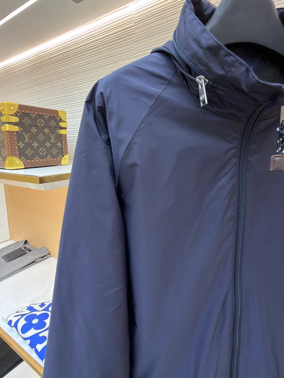 Prada Regenerated Nylon Fleece Jacket ●Original version: Purchased and developed by 12048 ●Item number: 1682331-B70 ●Fabric: Regenerated nylon fabric ●Technology: Made on positioning cutting machine ●Color: Navy blue ●Version: Fitted version ●Weight: about 585 grams ●Size: S-M-L-XL ●Description: High-density yarn is made by melt spinning through a special process. The yarn has been stretched and twisted through multiple processes to give the fabric the stiffness and wrinkle resistance that are comparable to those of native materials, while retaining a light and drapey wearing experience. The surface of the fabric is treated with an environmentally friendly coating process to form a micro-waterproof film layer, which is both windproof and breathable. The main raw material is polyester fiber blended wool raw material which is cleaned and pre-treated to remove impurities. After the yarn is woven into fabric through a loom, it is brushed, that is, the surface of the fiber is fluffed through mechanical brushing to form fluff. Then the shaking process is carried out, and the fabric is shaken under high temperature and humid conditions, so that the fibers form small spherical particles to increase the thermal insulation performance. The shoulder splicing uses twill sewing technology, the raglan sleeve design releases shoulder movement space, and the regular shoulder line ensures the stiffness of the overall silhouette, maintaining an elegant silhouette for both sports and static wear. The three-dimensional pleat design is incorporated into both sides of the body and sleeve elbows, and a long-lasting pleat texture is formed through high-temperature setting technology. This not only enhances the aerodynamic performance of the fabric, but also enriches the visual hierarchy with light and shadow changes, breaking the dull feeling of solid color fabrics. The cuffs are equipped with a hidden snap-button adjustment system, which can be freely tightened according to the circumference of the wrist to prevent cold wind from entering; the straight bottom edge is matched with a drawstring at the hem, and the inner rope buckle design can be used to adjust the tightness, taking into account warmth preservation and waistline shaping. The overall wiring is straight and delicate, the fabric is comfortable and soft, and the color is consistent without color difference. It can be matched with the same style to create a fashionable look and control various occasions. Customized accessories, complete with three standards, same style for men and women!